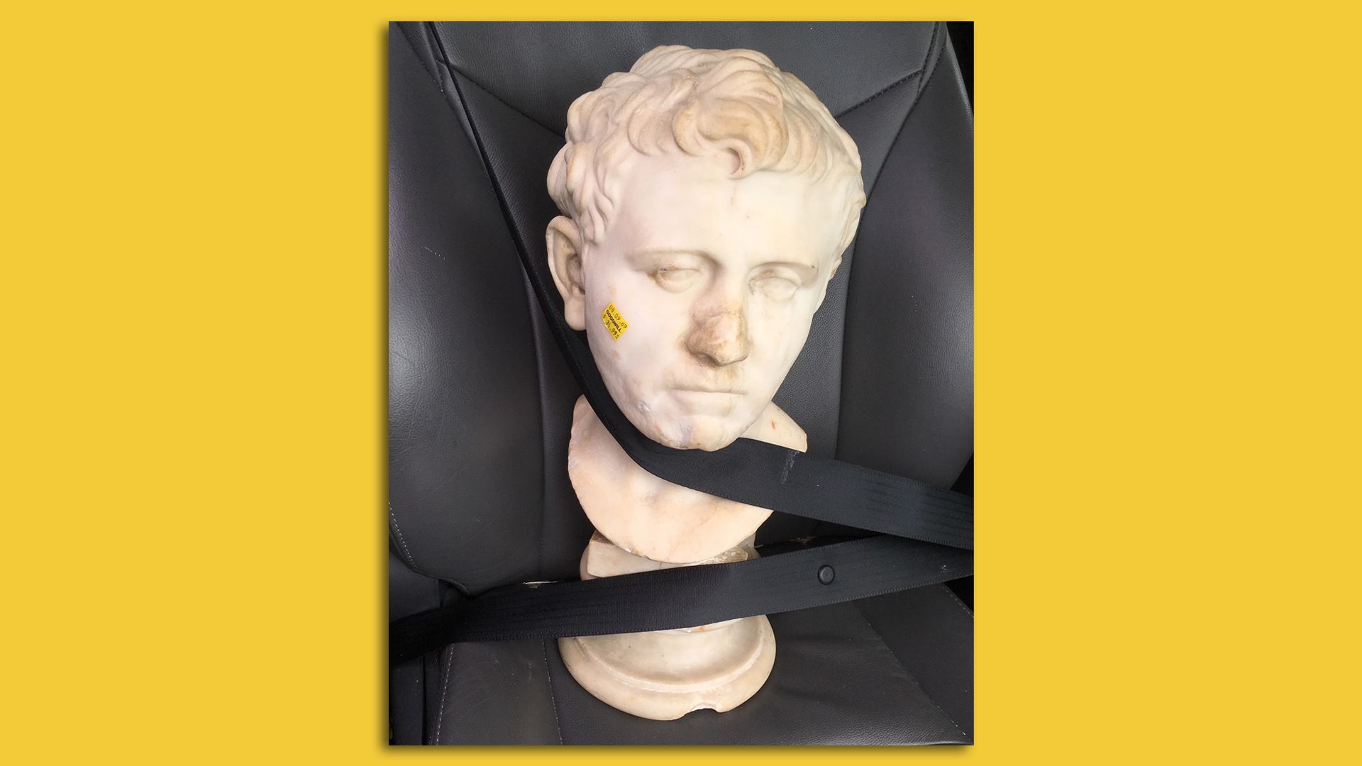 Sculpture buckled into a car seat.