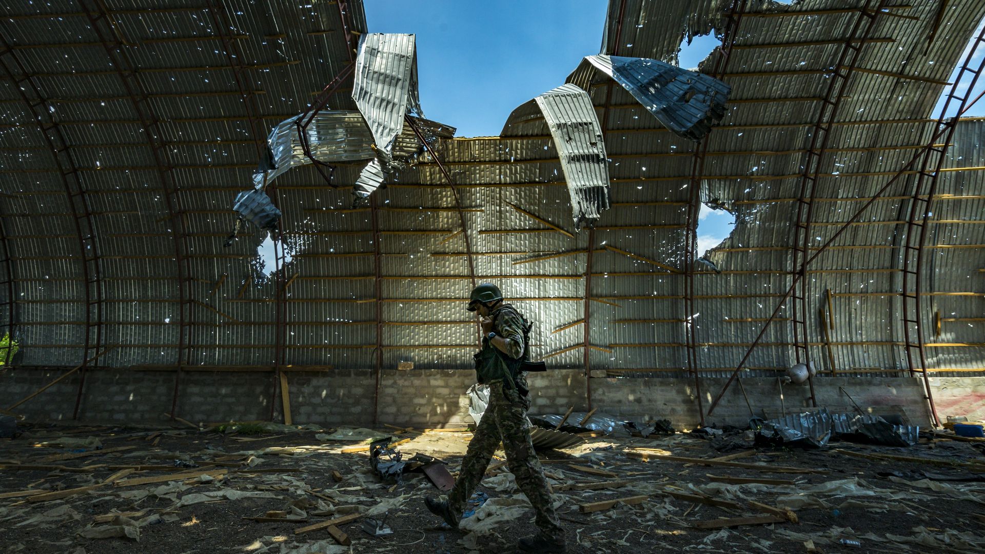 Ukrainian soldier walking past a destroyed barn