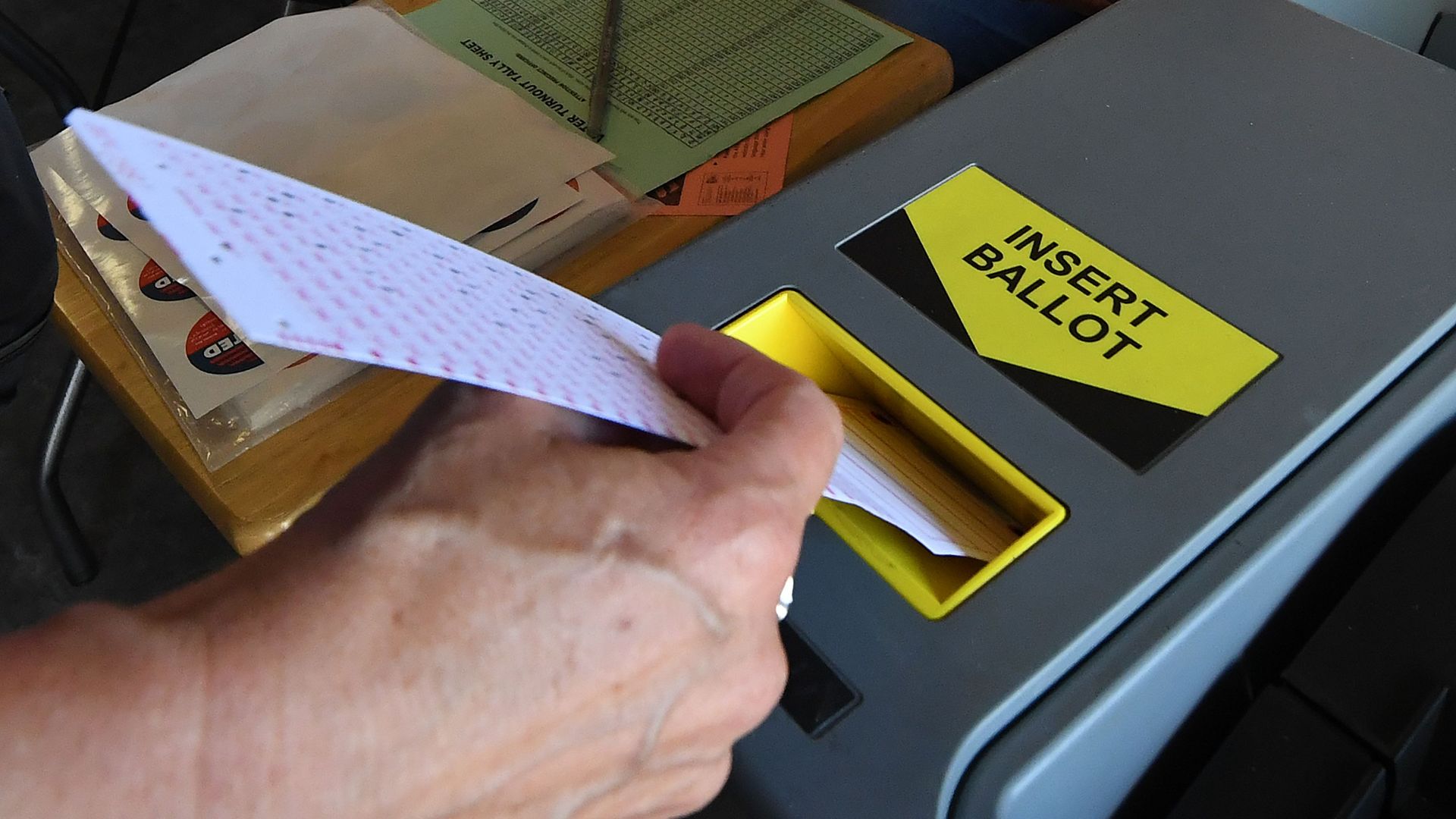 A woman puts a ballot into a scanning machine