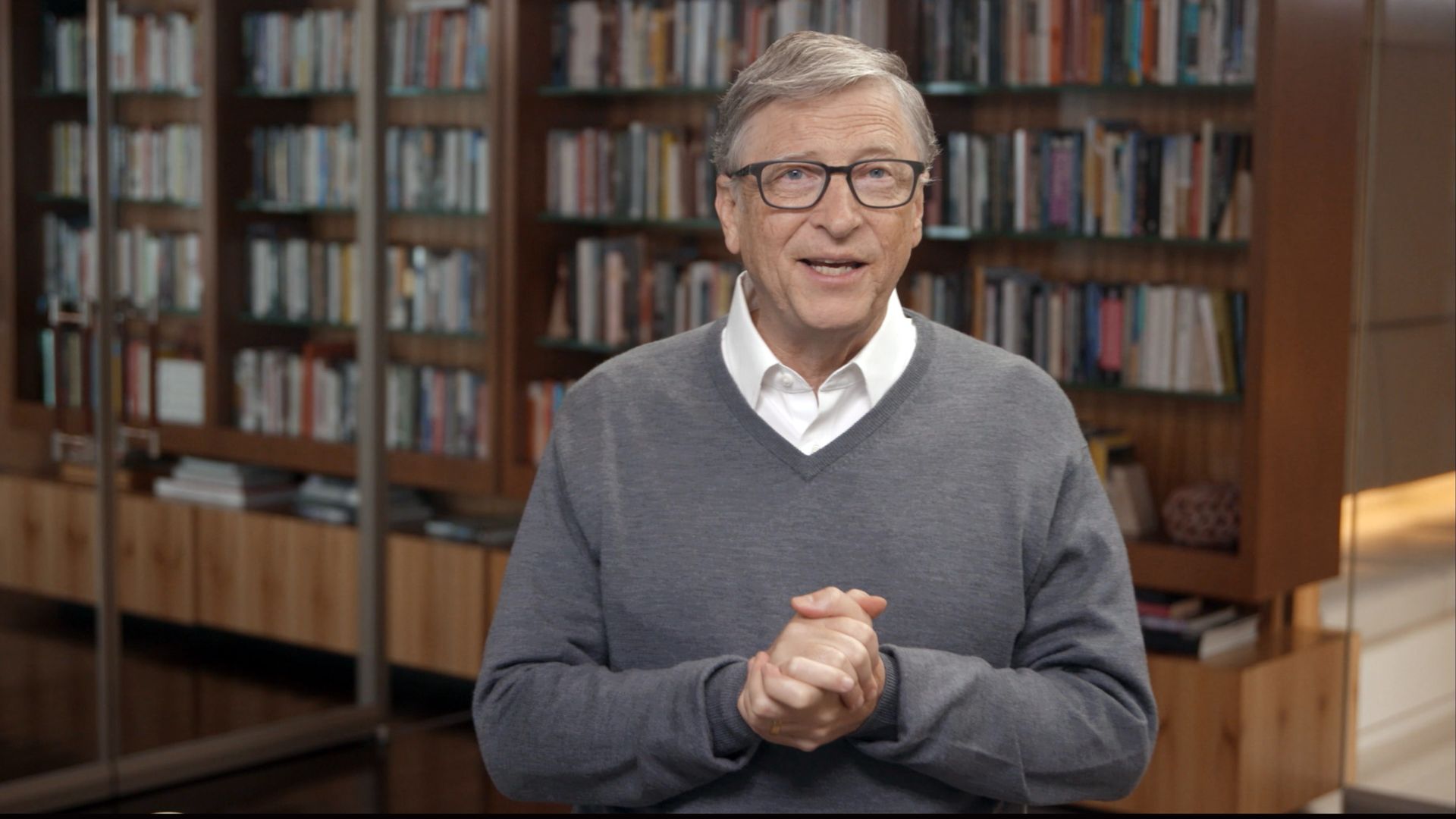 A photo of Microsoft co-founder Bill Gates in front of a library of books