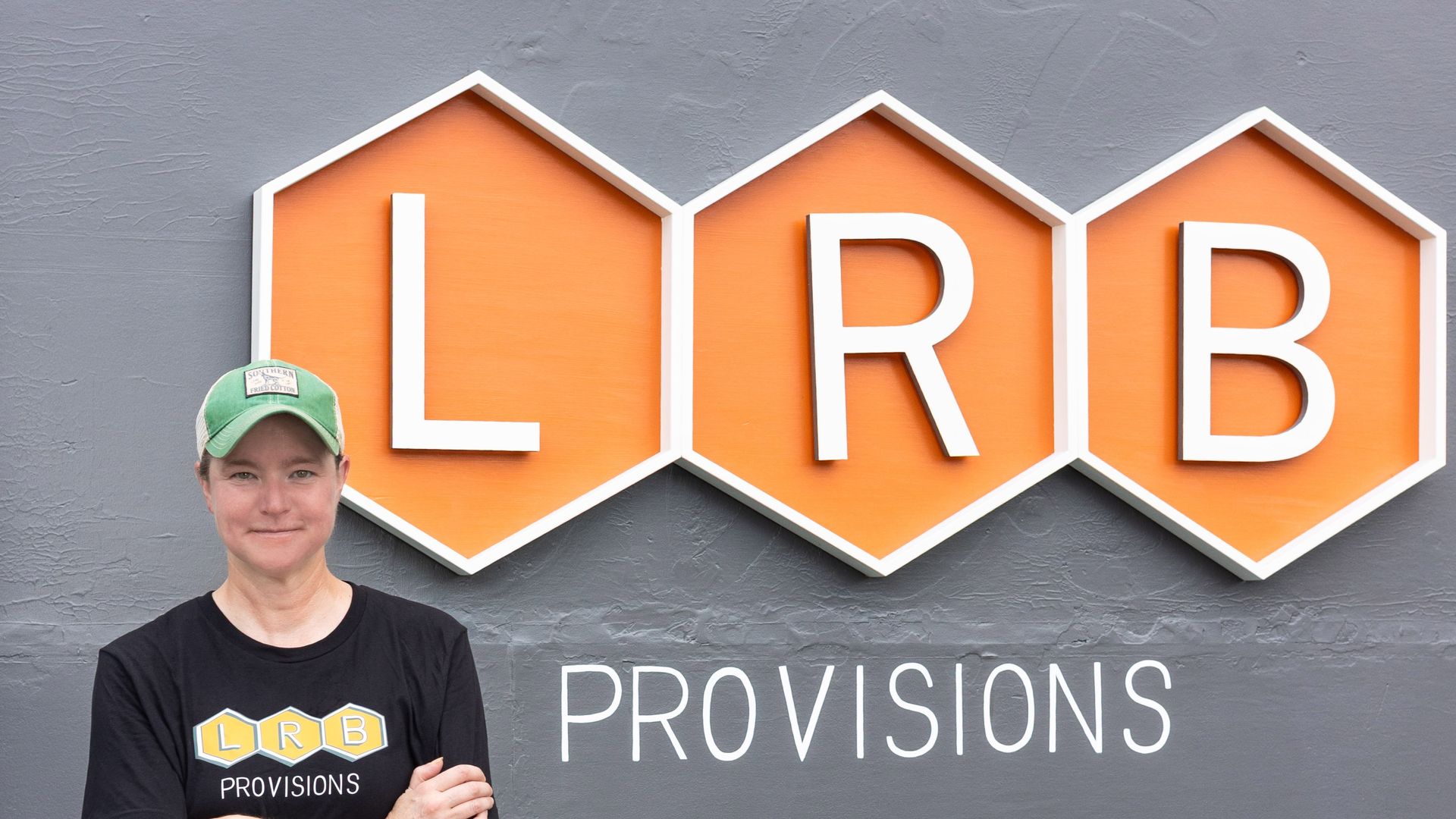 Chef Amanda Orser stands in front of an orange sign that says LRB Provisions