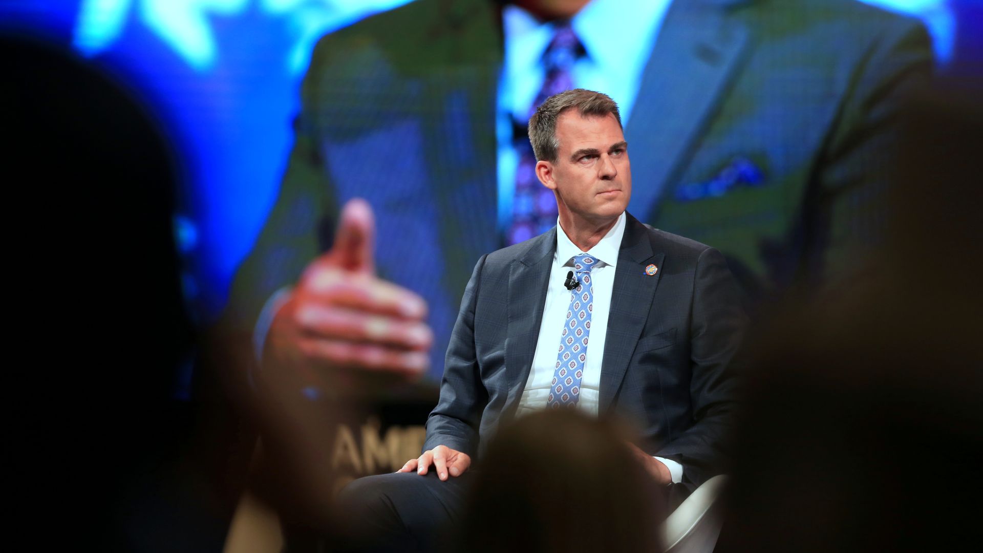 Photo of Kevin Stitt sitting on stage in front of an audience