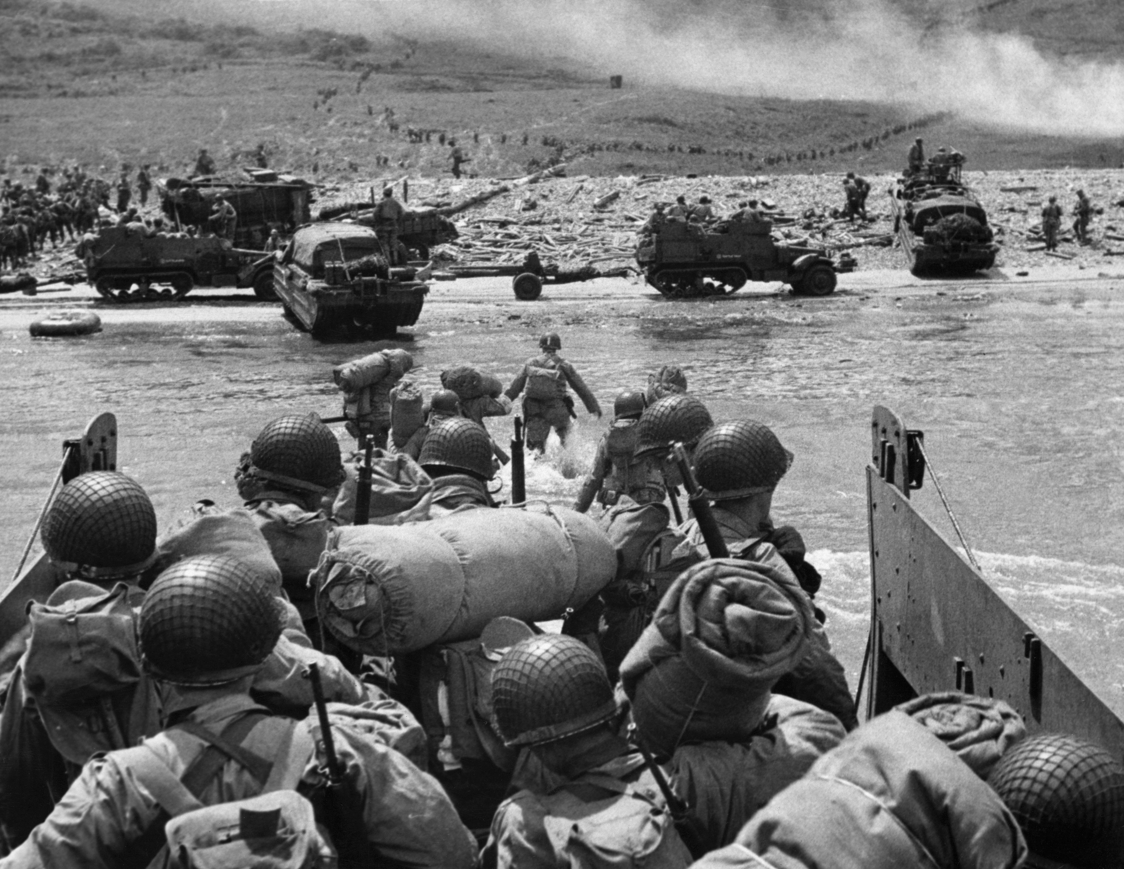 Black and white photo shows soldiers going ashore on D-Day.