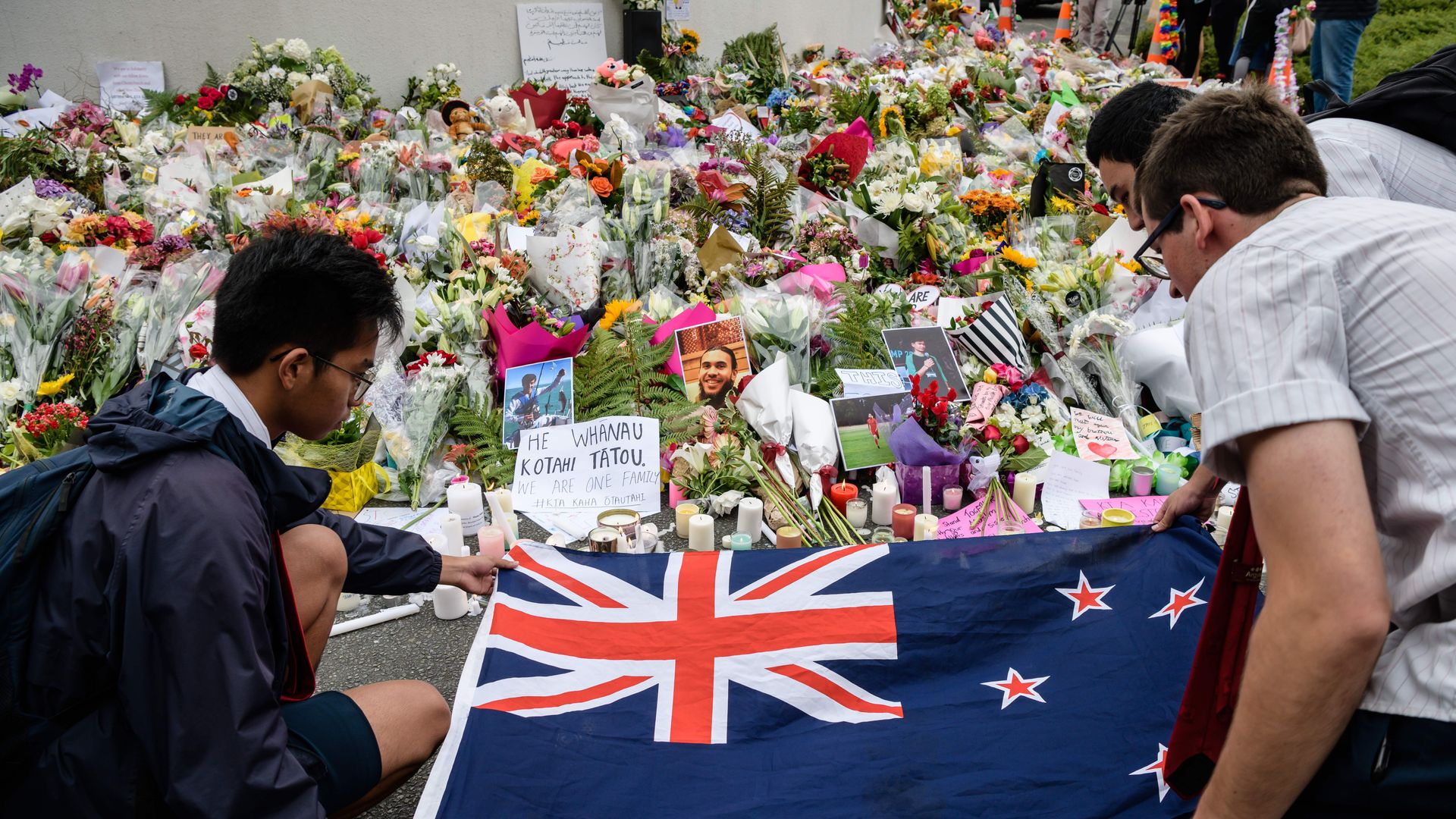 Students display the New Zealand national flag next to flowers during a vigil in Christchurch on March 18, 2019.