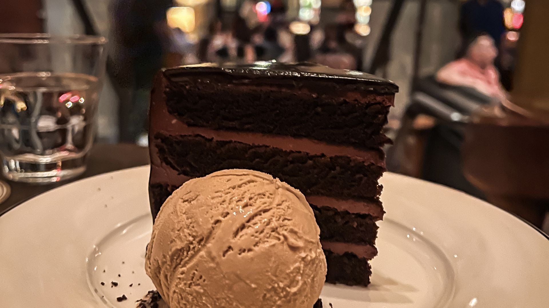 A multi-layer chocolate cake plated with a scoop of ice cream. 