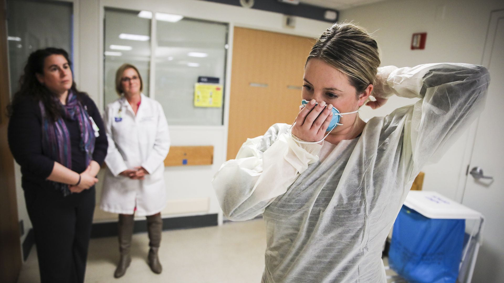 A nurse shows how to don a surgical mask to protect against the coronavirus.