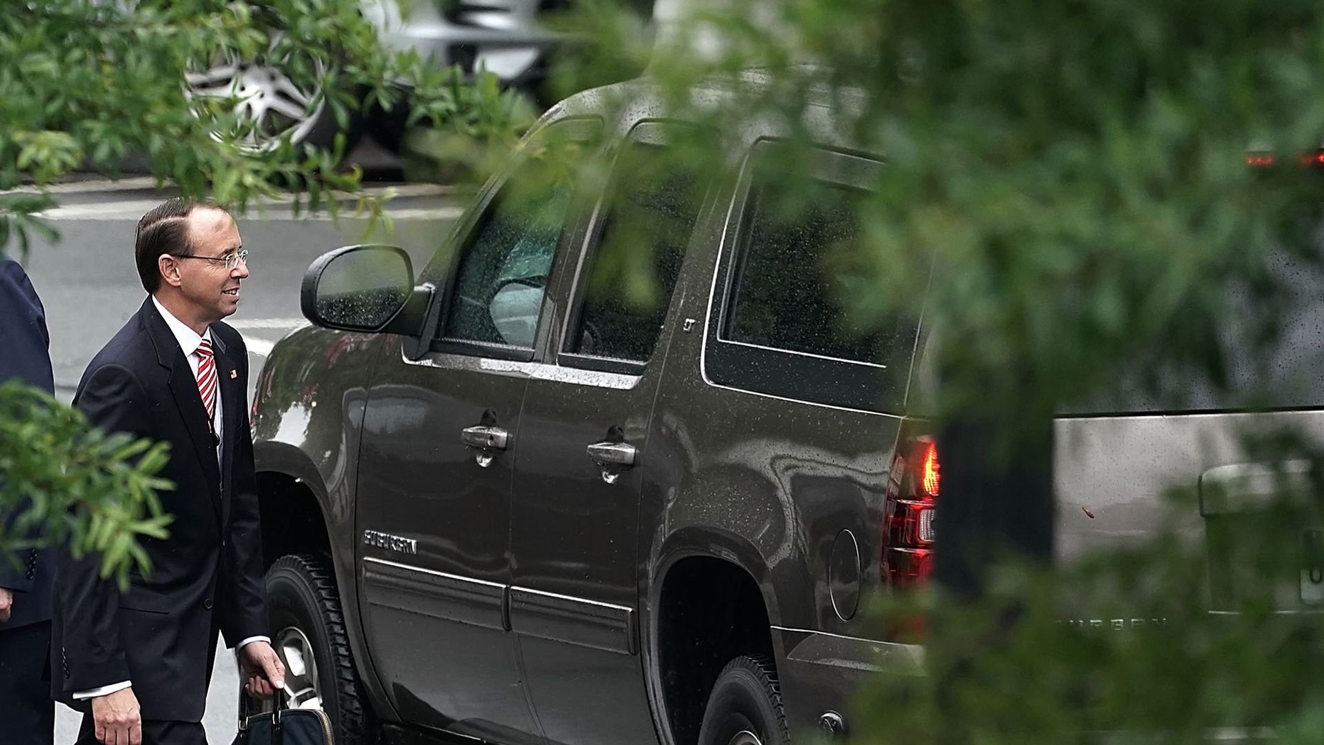 Rod Rosenstein walking near a car, with a tree shrouding the picture