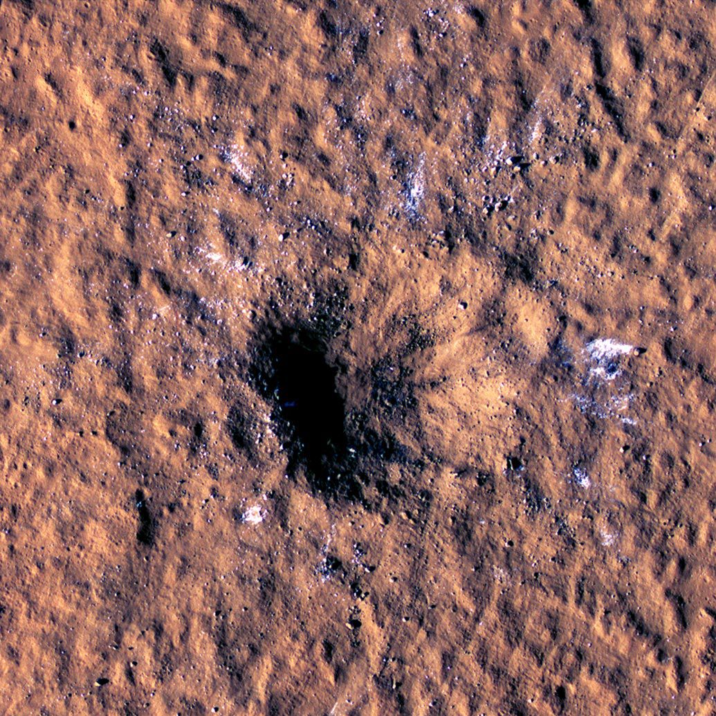 In this image made available by NASA on Thursday, Oct. 27, 2022, boulder-size blocks of water ice are seen around the rim of an impact crater on Mars.