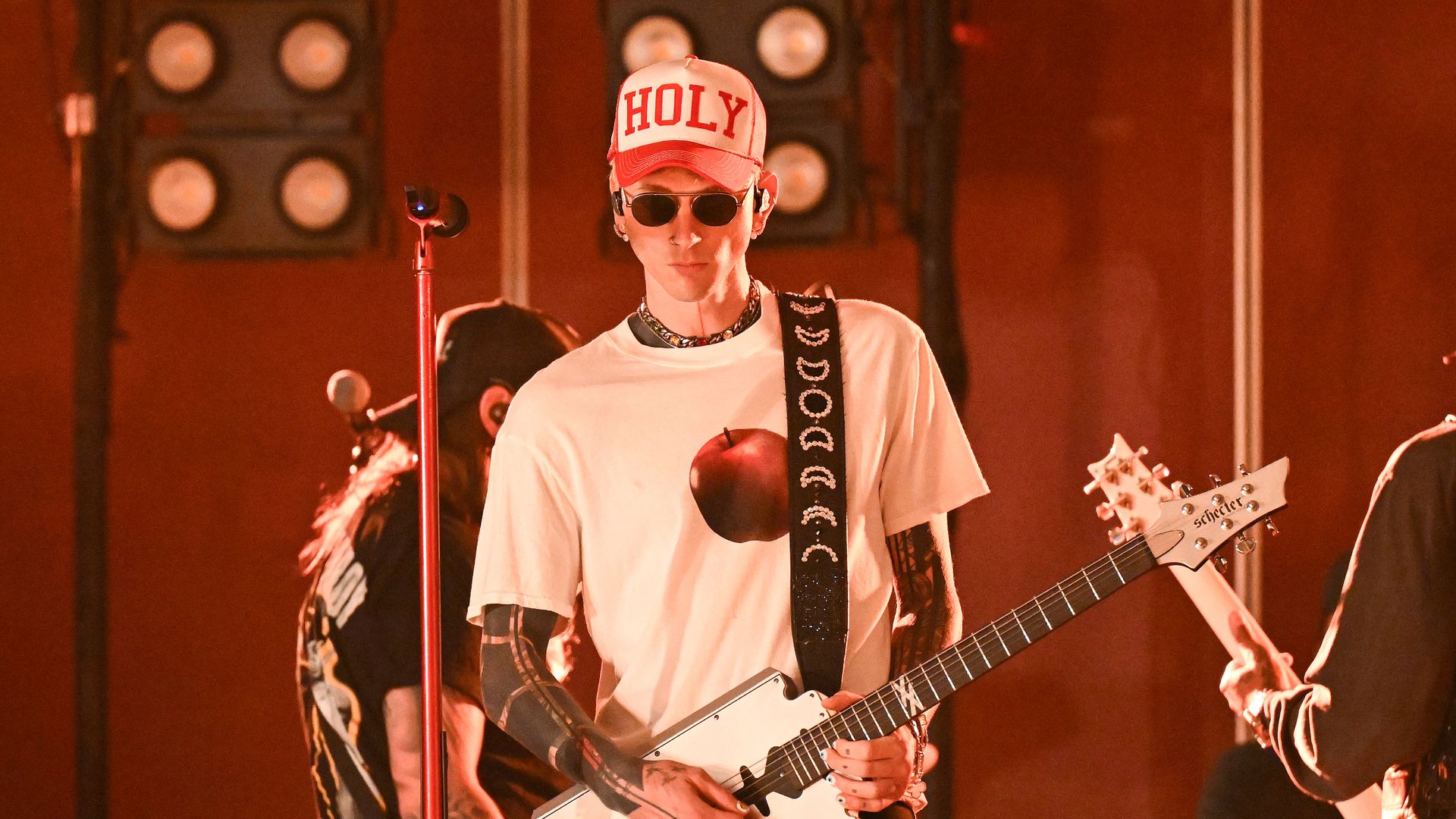 Machine Gun Kelly plays guitar on stage. 