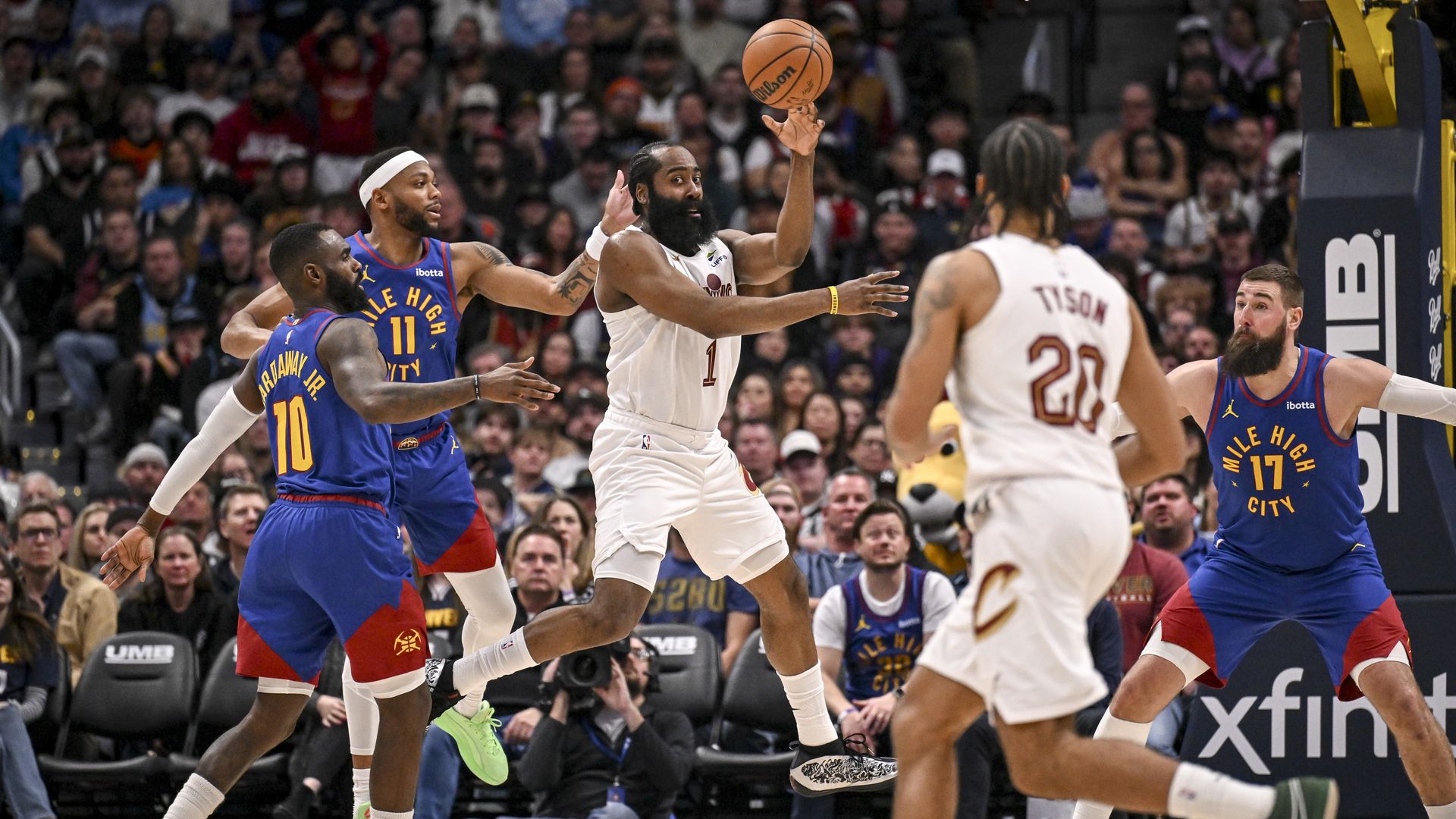 NBA game in action. Bearded black man in white jersey thread pass between three defenders in blue. 