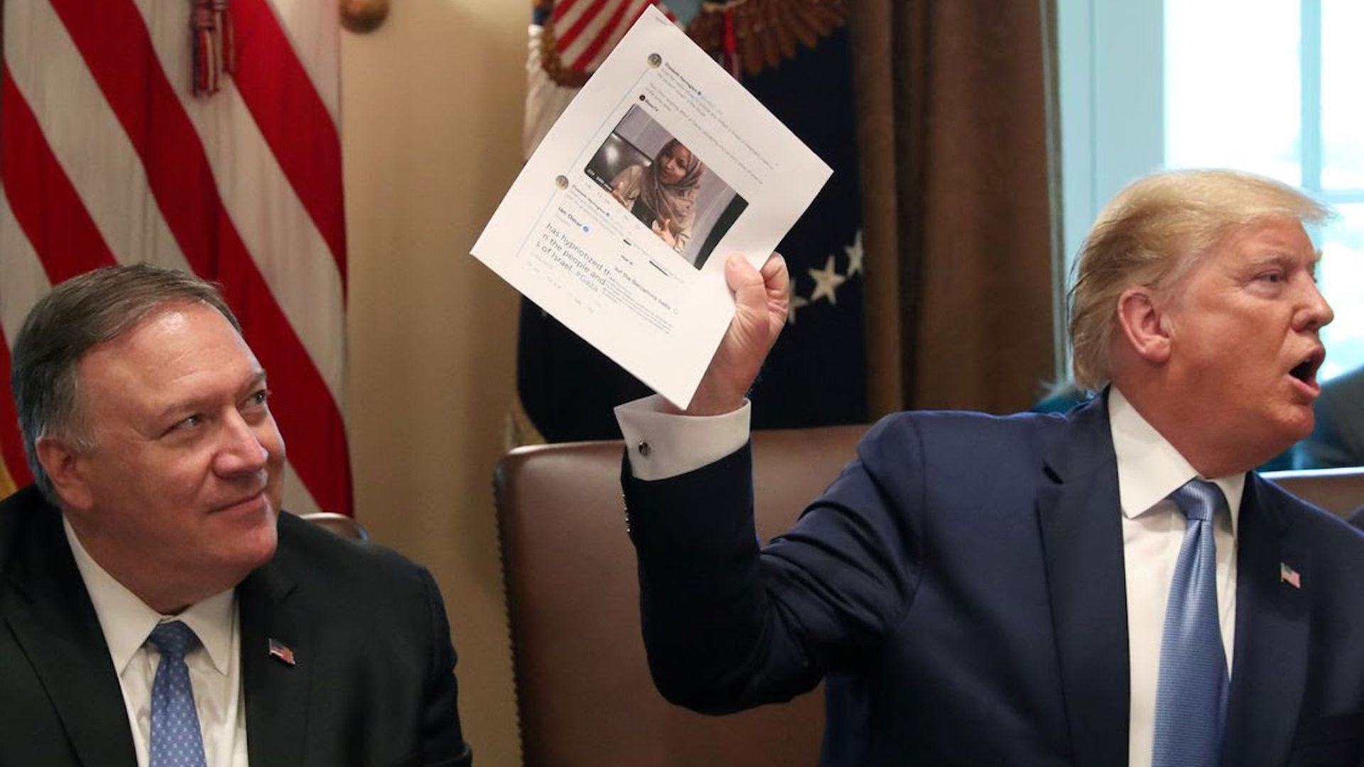 President Trump with Sec. of State Mike Pompeo has he waves around a sheet with Rep. Ilhan Omar's face on it