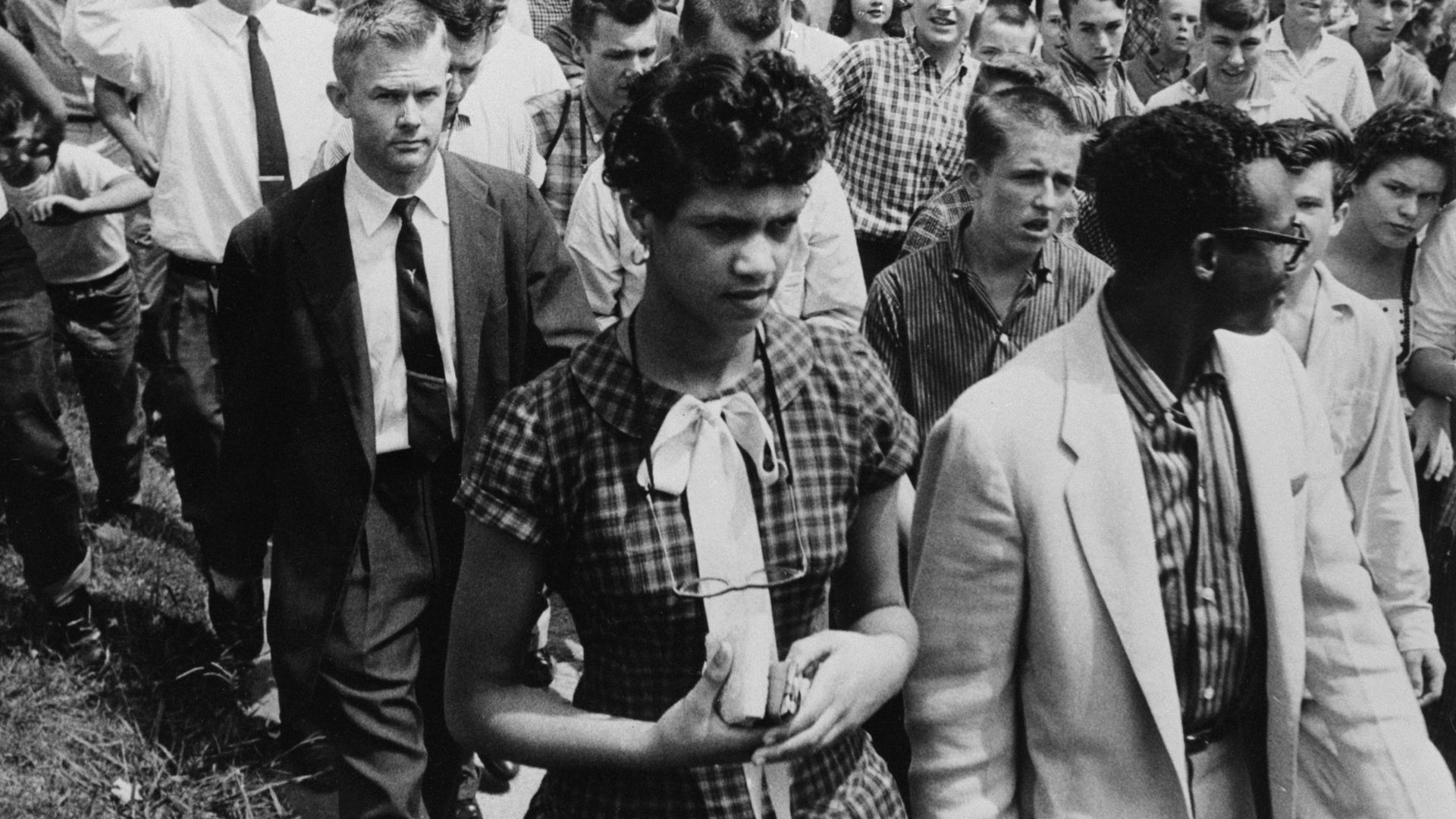 Dorothy Geraldine Counts, 15 (left) is followed by a crowd of jeering teenagers as she leaves Harding high school with her escort, Dr R.A. Hawkins, 4th September 1957. The crowd of about 100 youths pelted Dorothy and her escort with sticks and stones after she enrolled at the White high school in Ch
