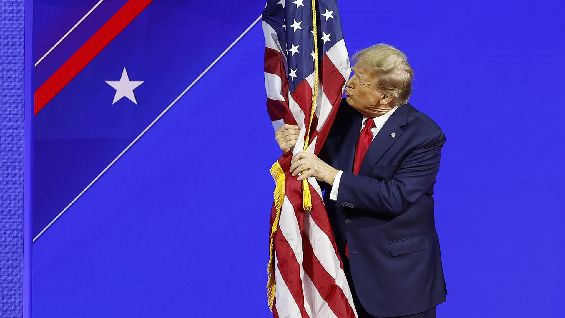 Trump grabs an American flag as he pretends to kiss it.