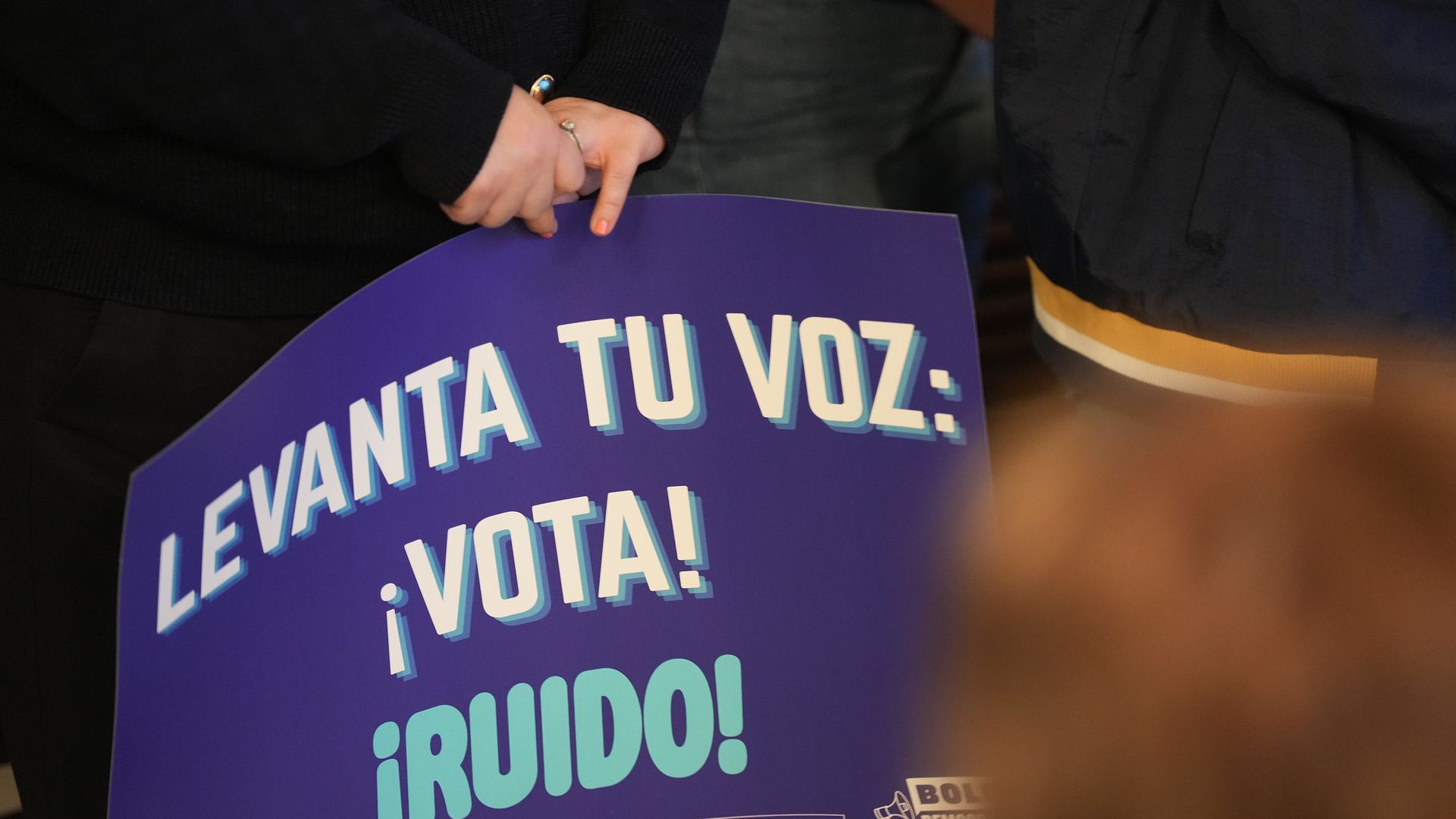A sign in Spanish says, "Raise your voice: Vote!"