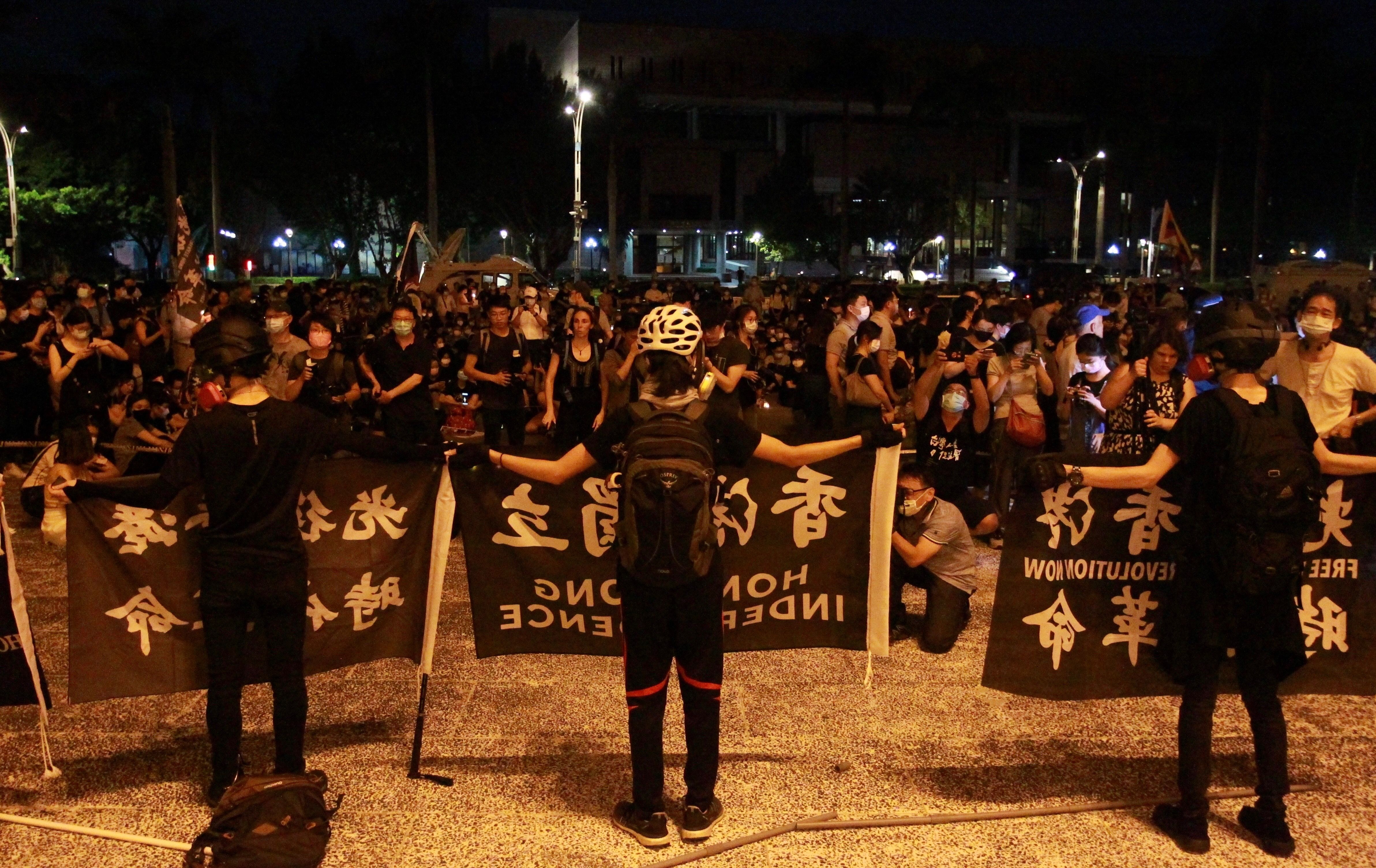 A line of people wearing masks hold banners 