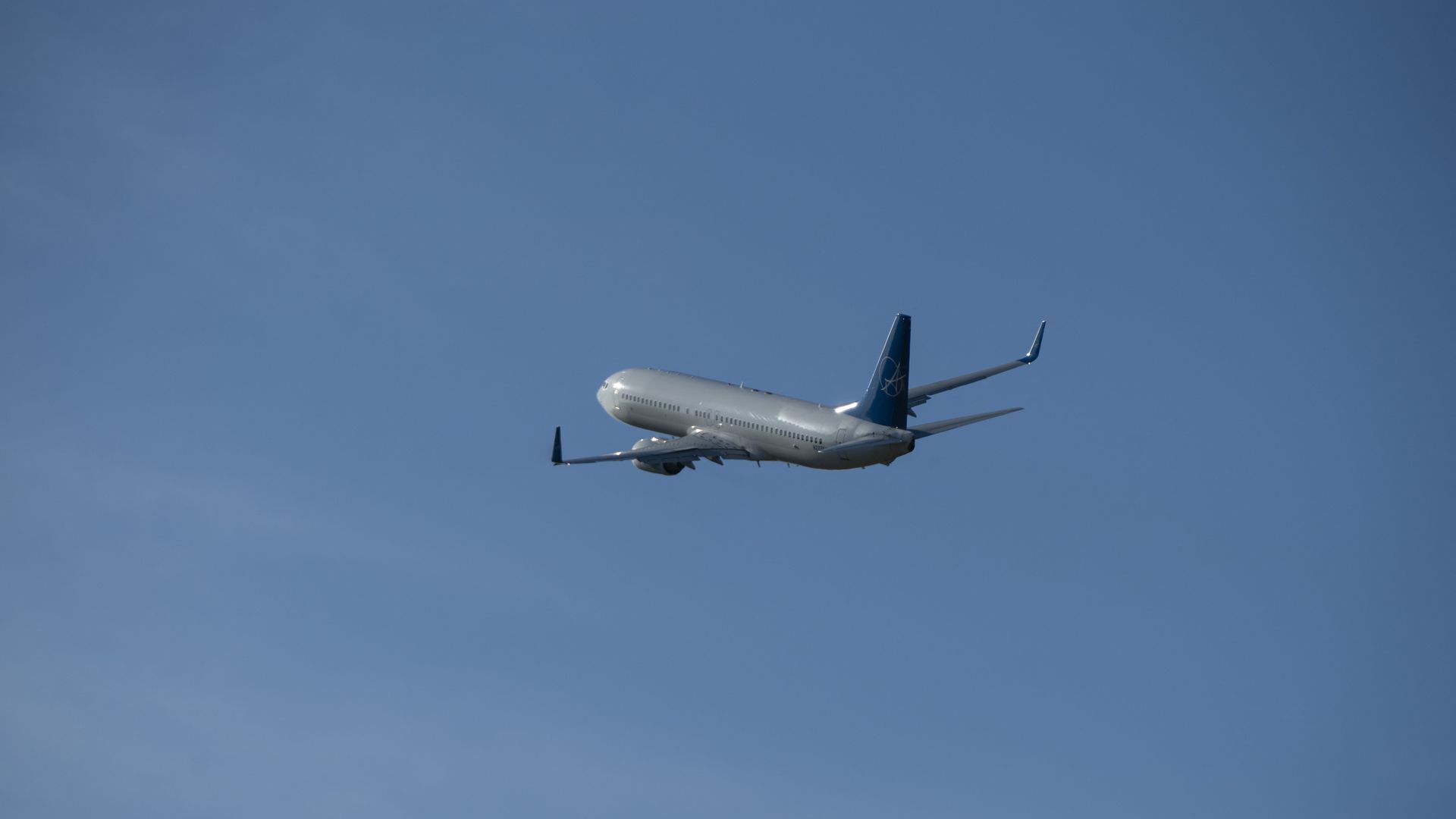 An airplane is shown flying in a blue sky