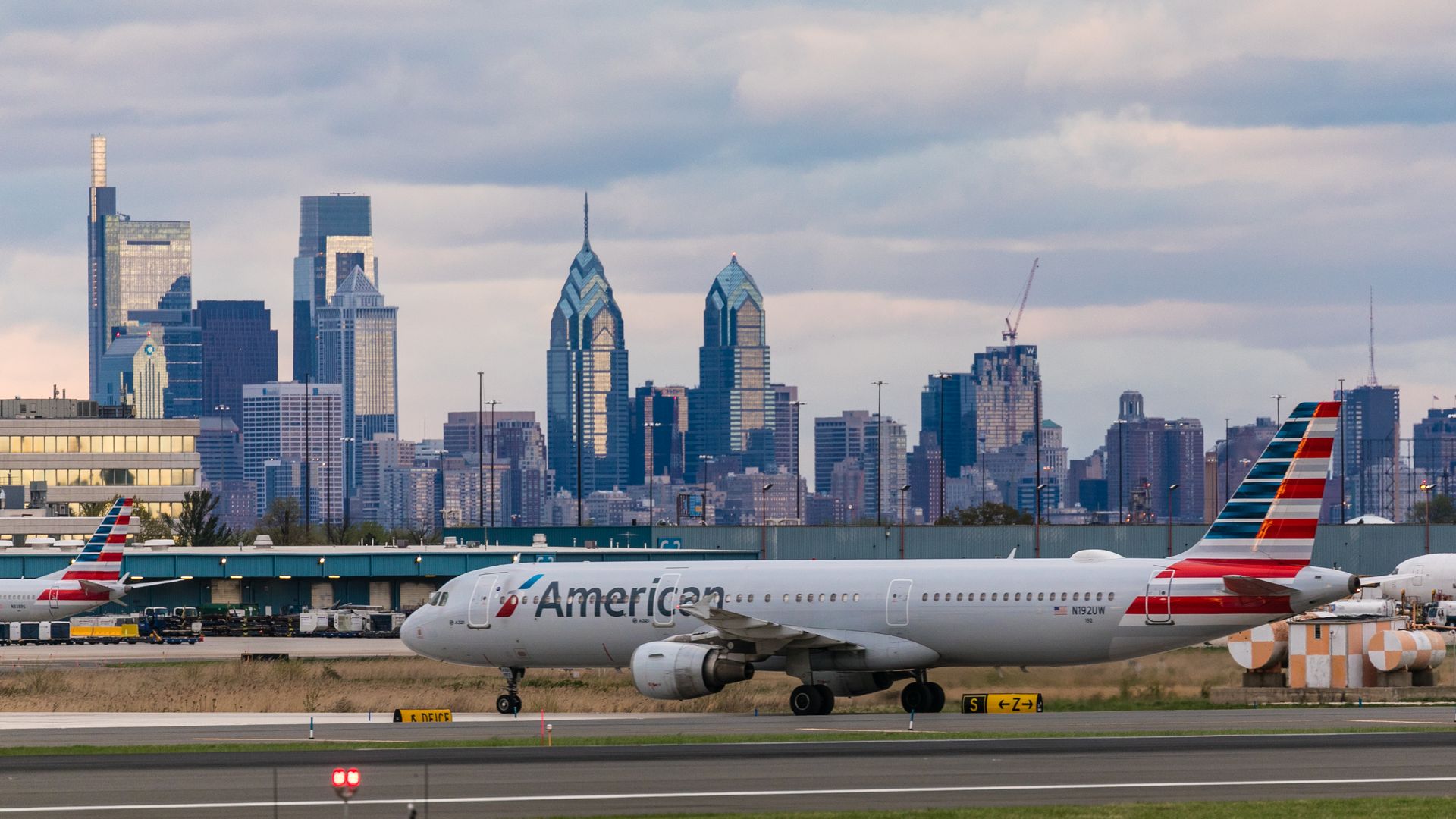 An airplane on a runway in front of the Philadelphia skyline