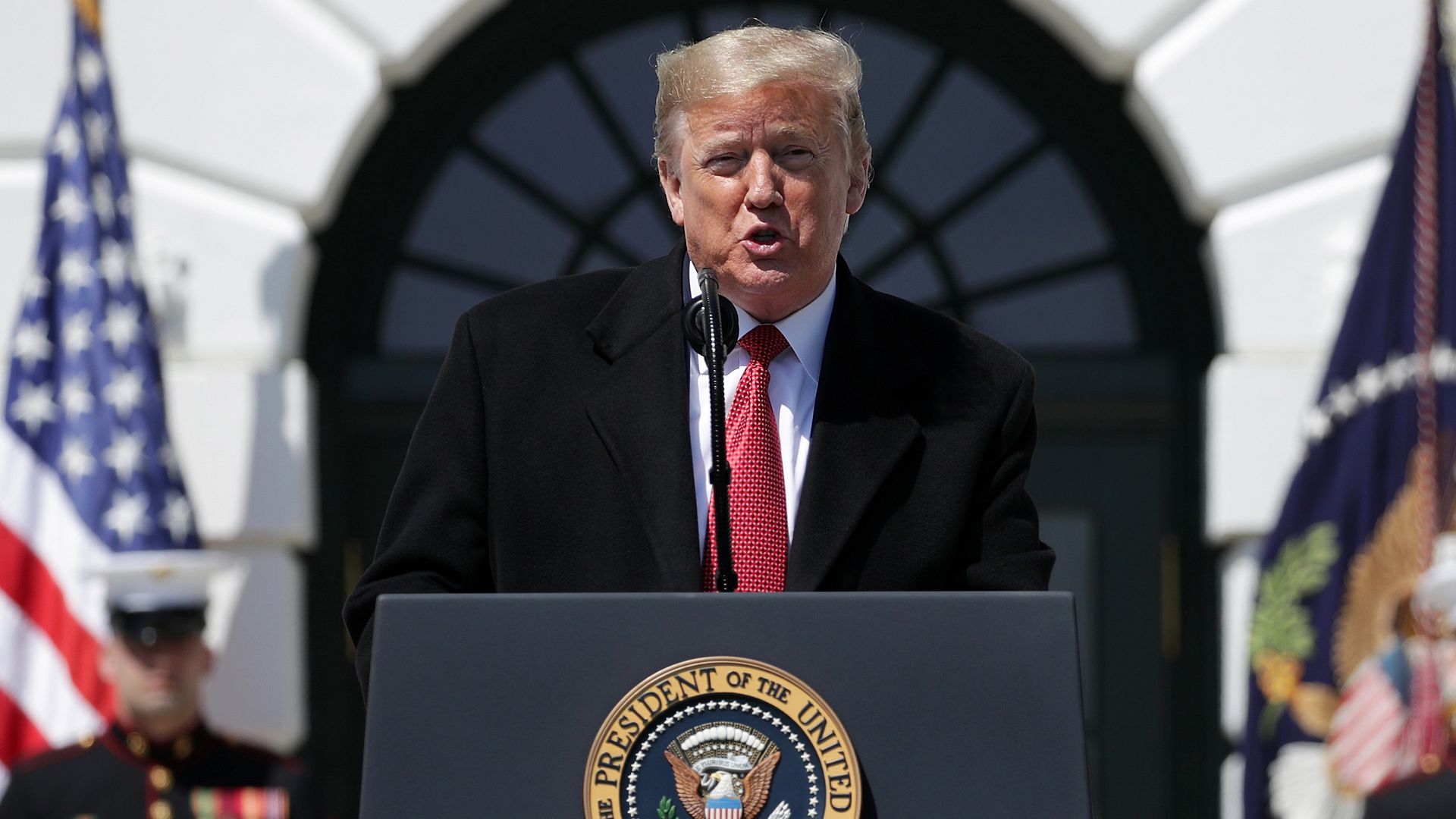 In this image, Trump stands in front of a podium
