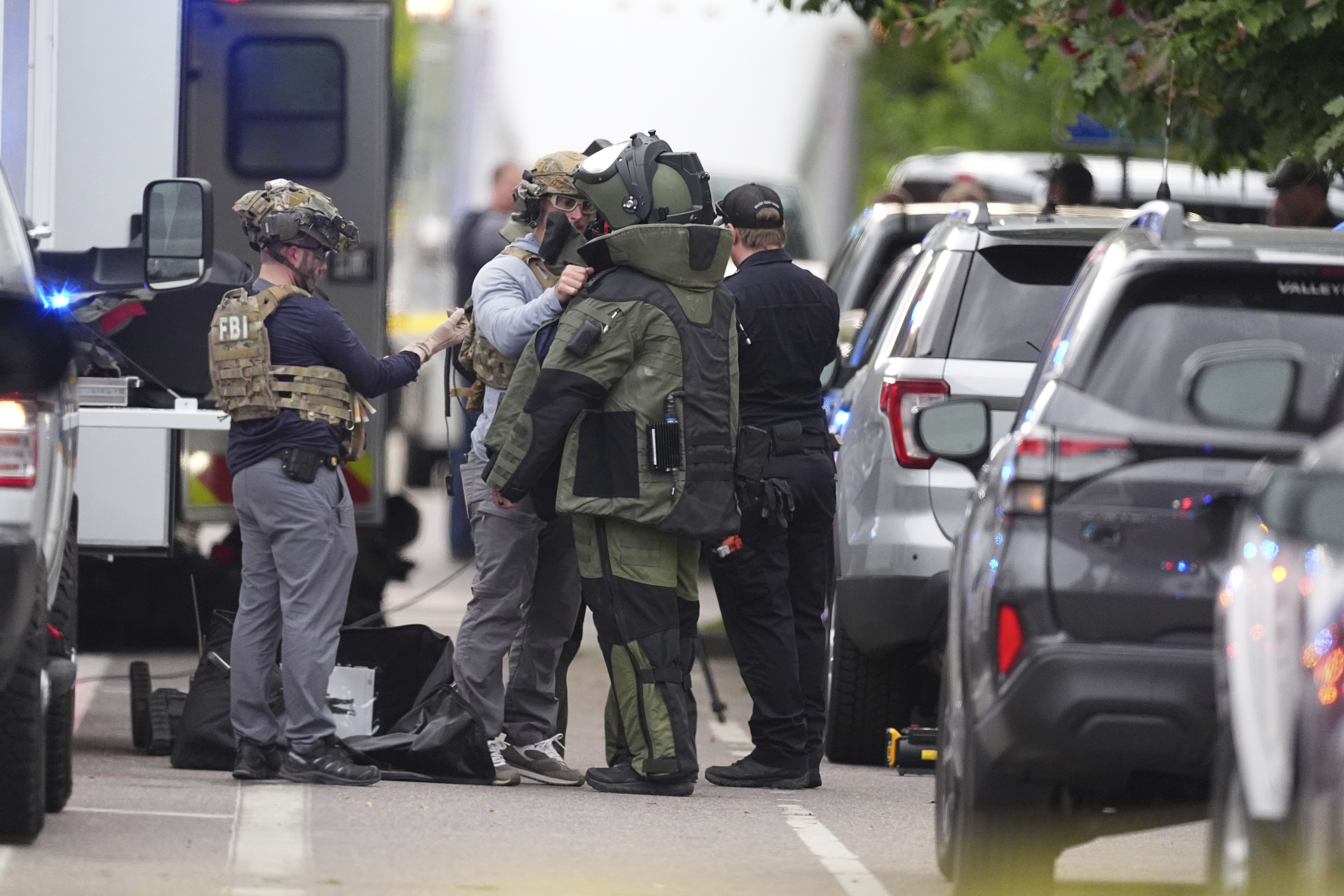 Law enforcement officials dress up in protective gear to investigative an attack in Boulder yesterday.