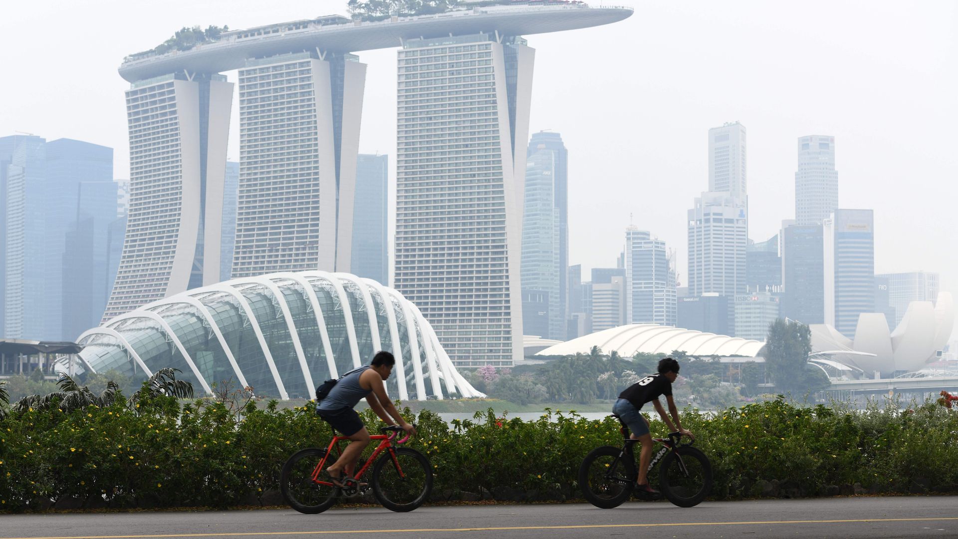People cycle before the city skyline on a hazy day in Singapore in September.