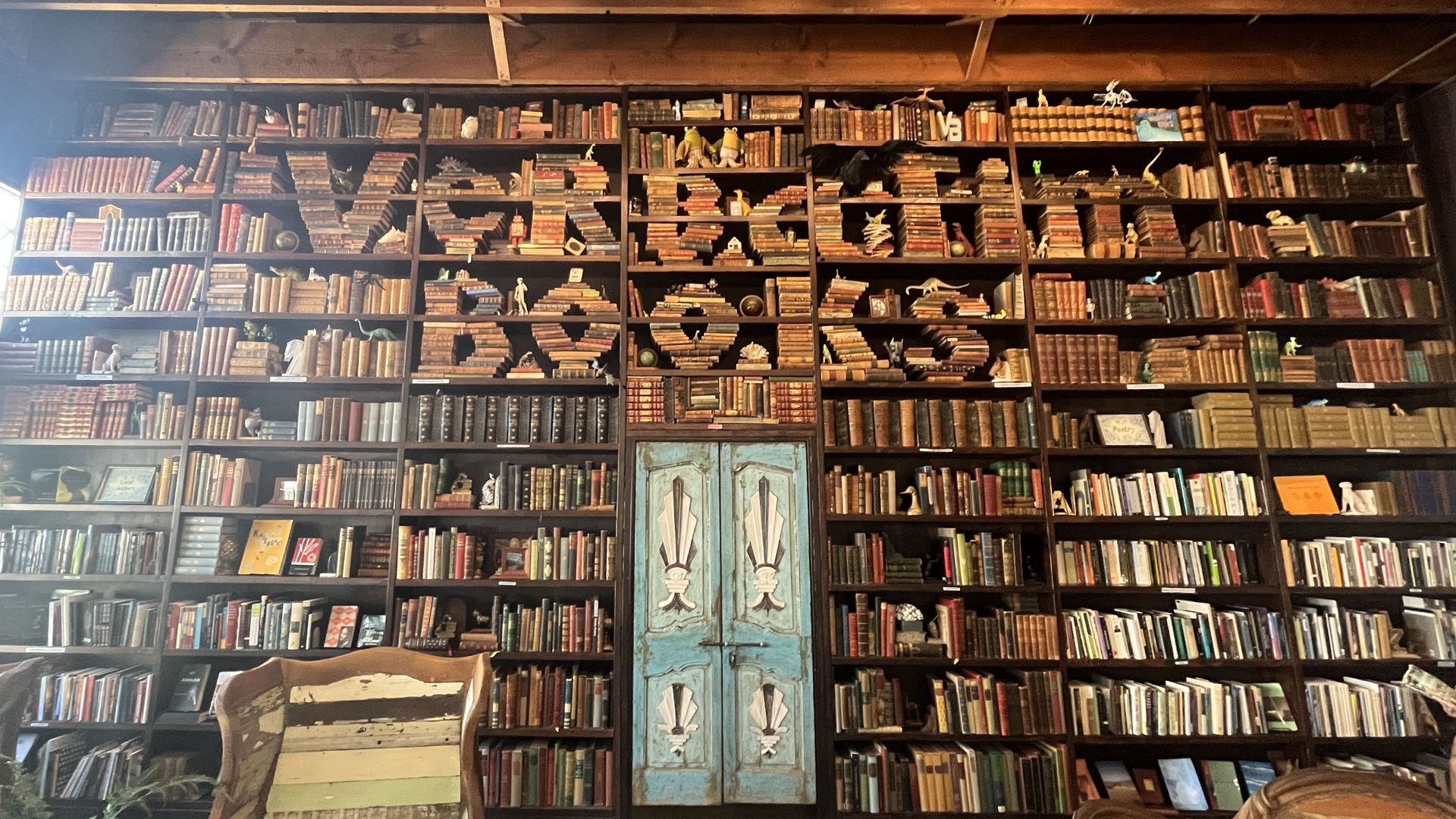 A local store's floor-to-ceiling bookshelf filled with books that spell "Verbatim Books."