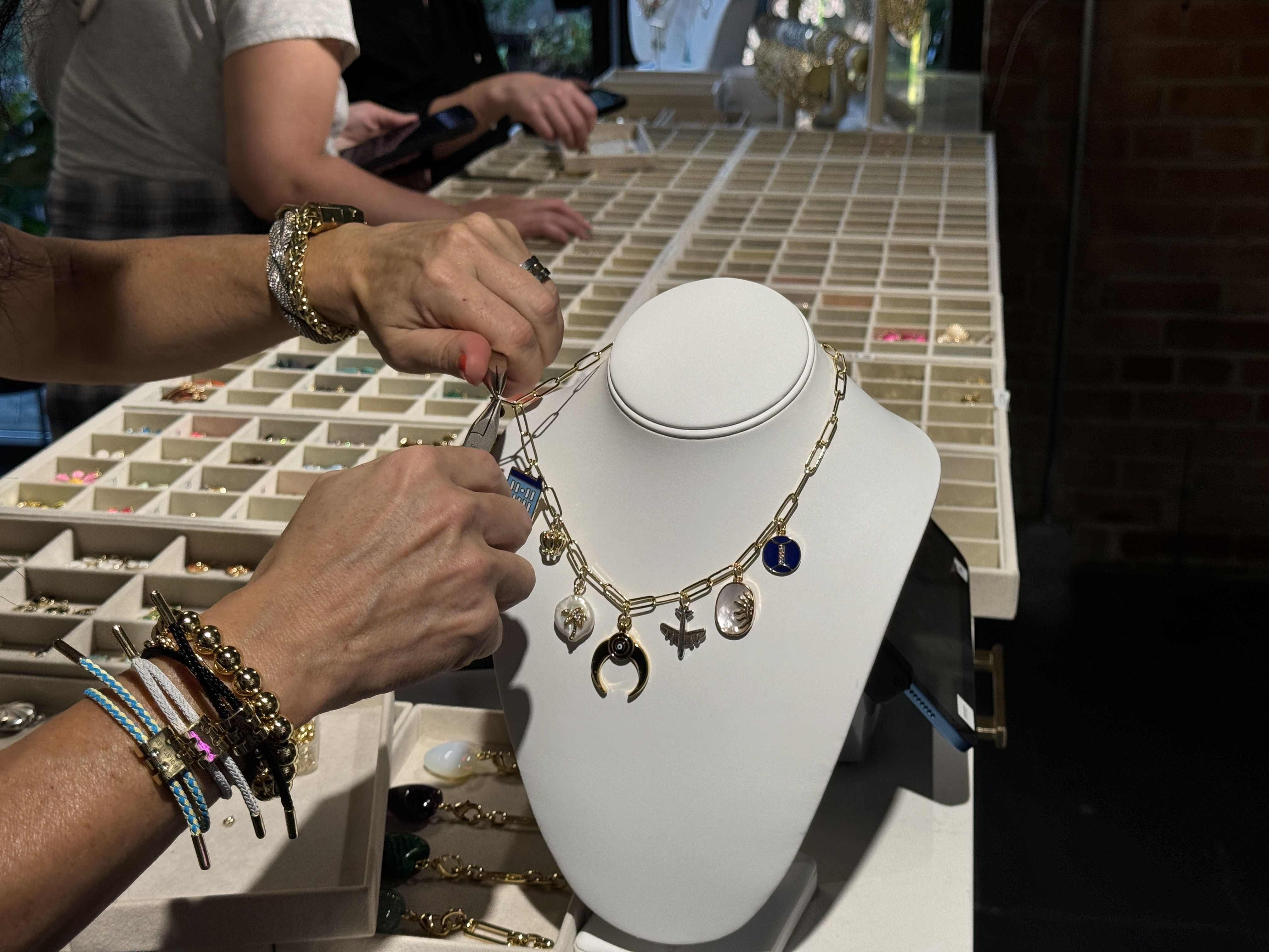 two hands fastening a charm onto a necklace