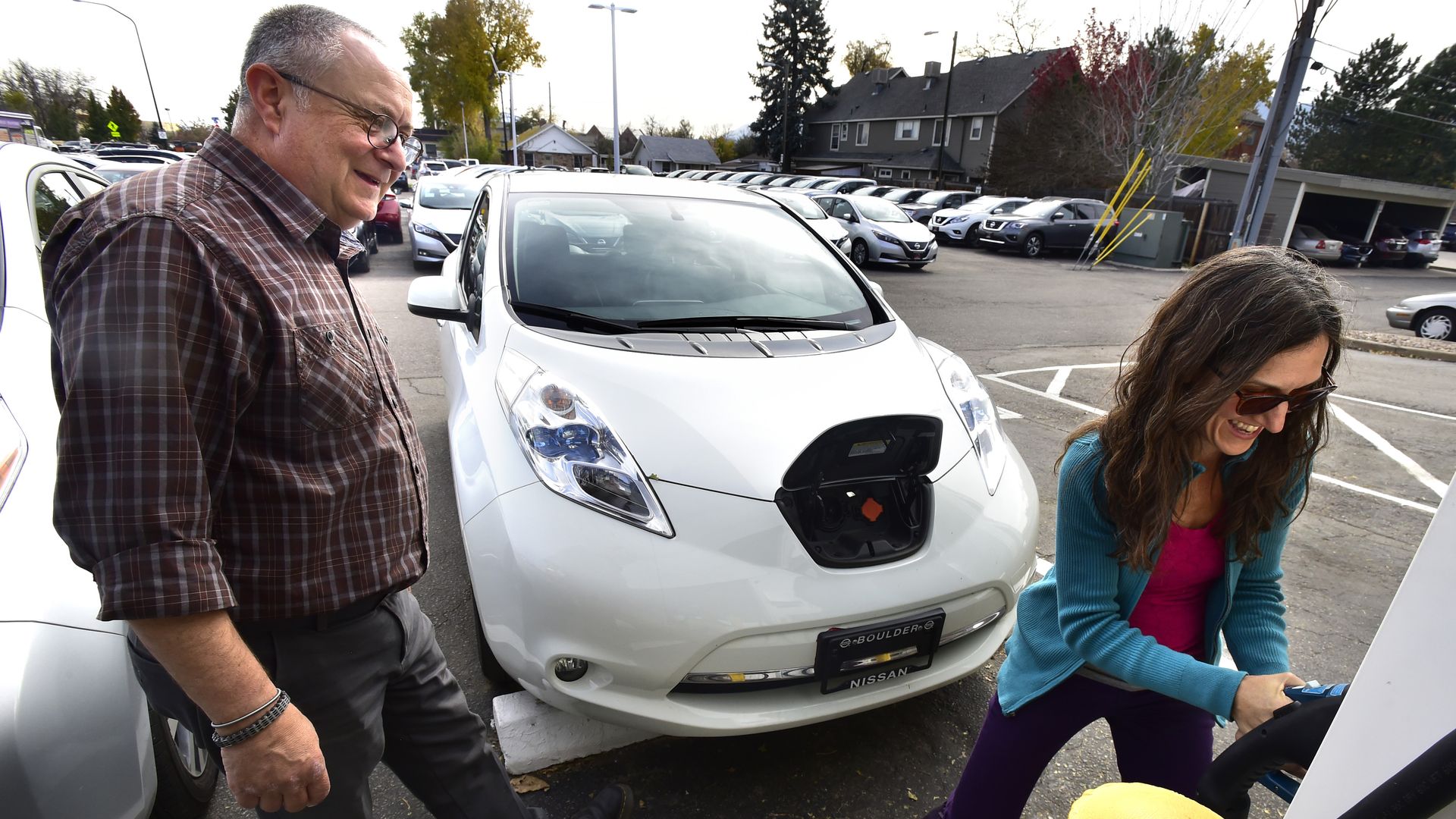 Shanna Solla laughs as she learns how to use the electric charging station with her new Nissan Leaf.