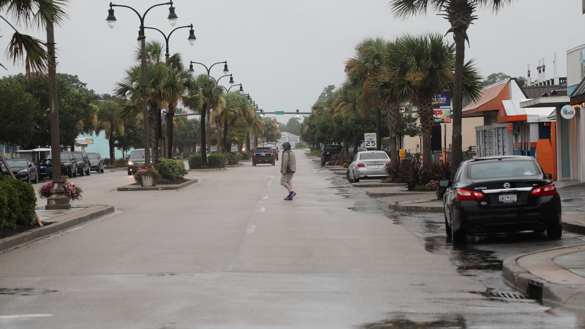 A man walks across the street in downtown North Myrtle Beach as Tropical Storm Isaias approaches the South Carolina coastline on August 3
