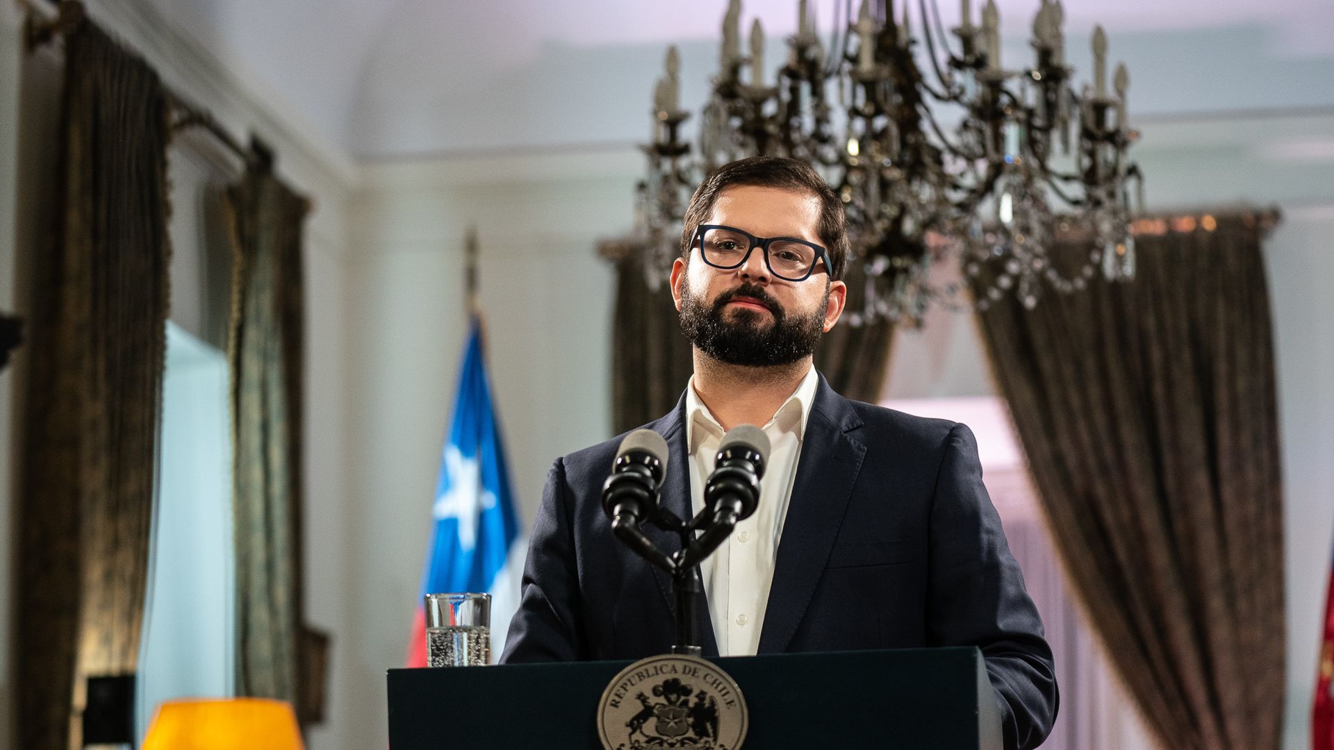 Chile President Gabriel Boric stands behind a podium and in front of two microphones during a news conference on Sunday 