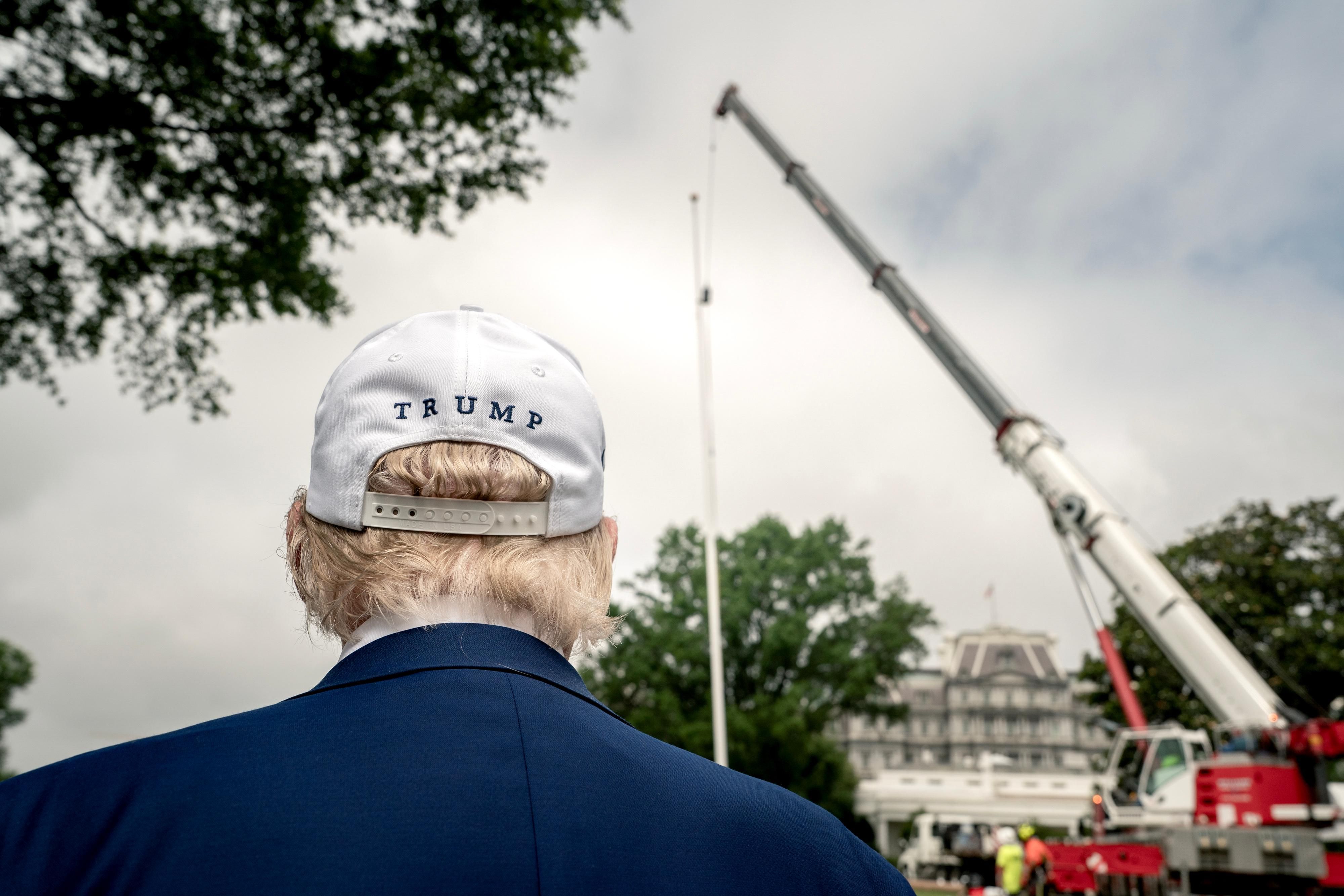 President Trump watches as workers install a new flagpole on the South Lawn yesterday.