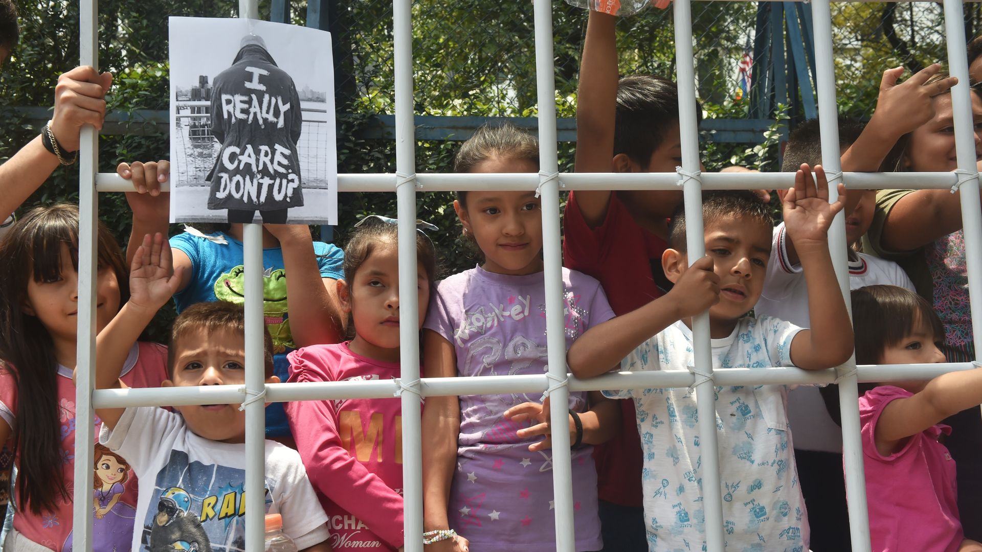 children protesting family separation by standing behind fake jail bars 