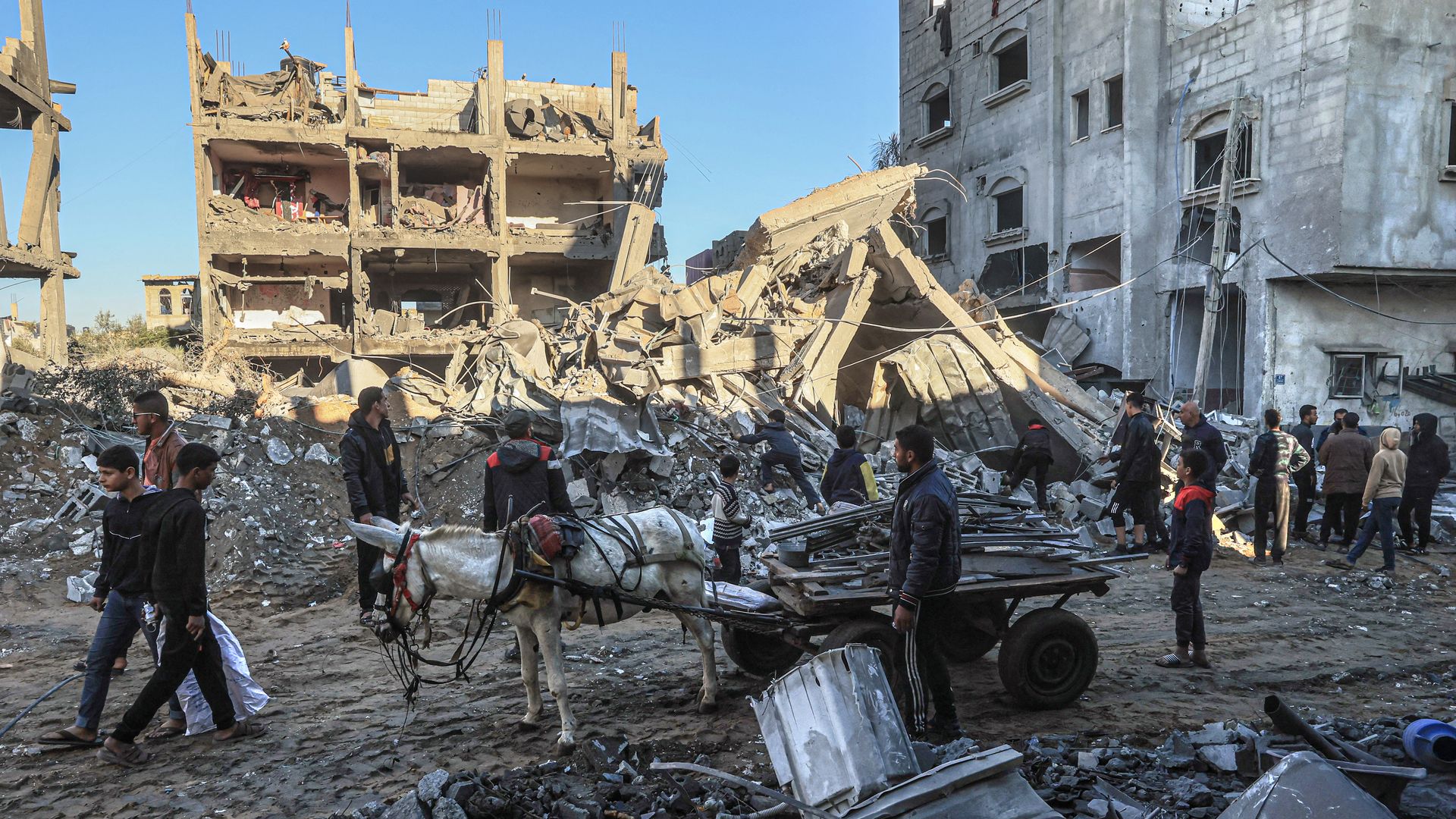 Palestinians walk past the rubble of buildings destroyed following Israeli bombardment on Rafah, in the southern Gaza Strip