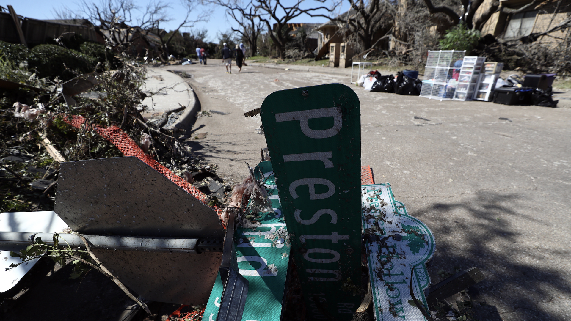 A twisted street sign in front of a ton of tornado wreckage