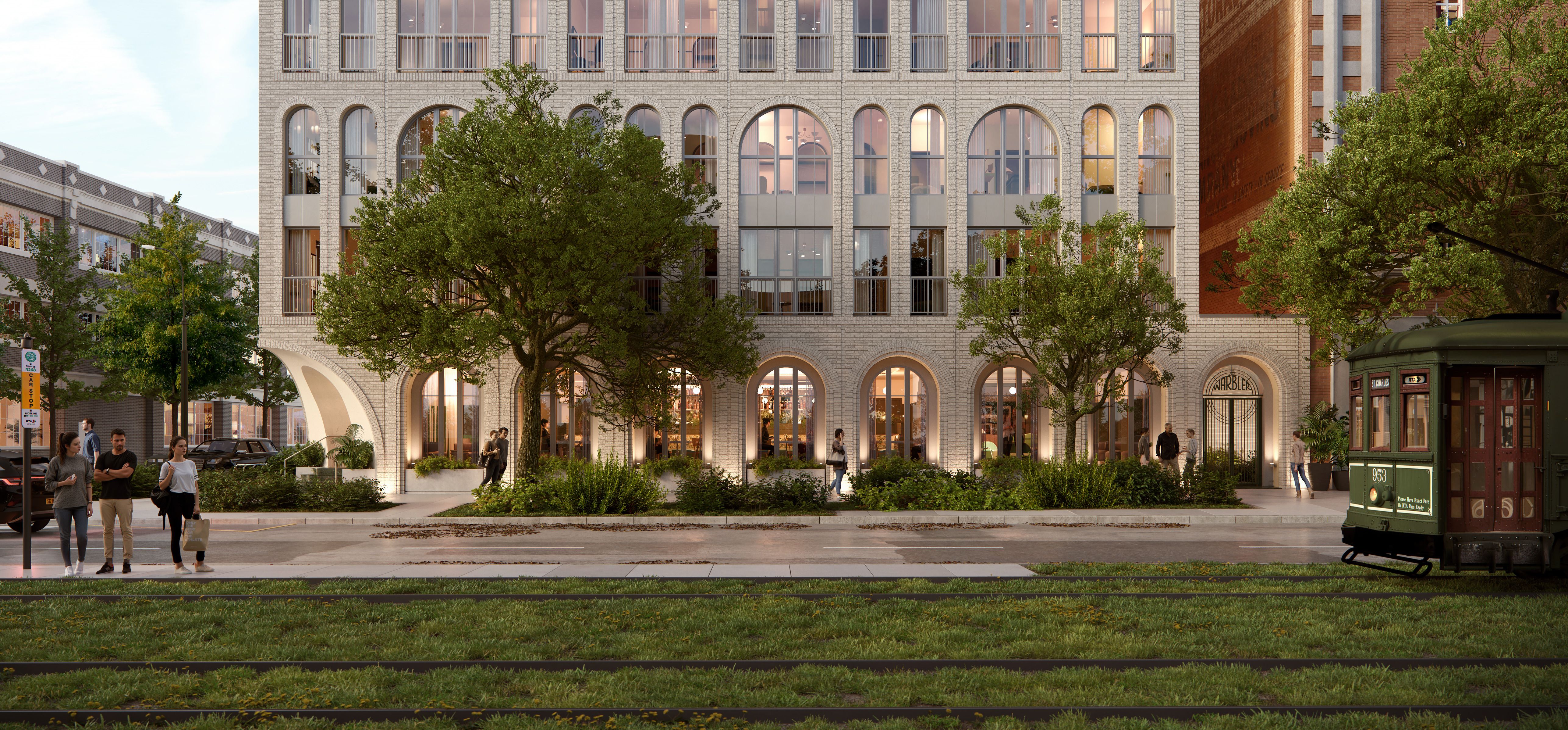 A modern light brick building with arched windows and greenery in front, people walking nearby, and a green streetcar rambles on tracks into the foreground.