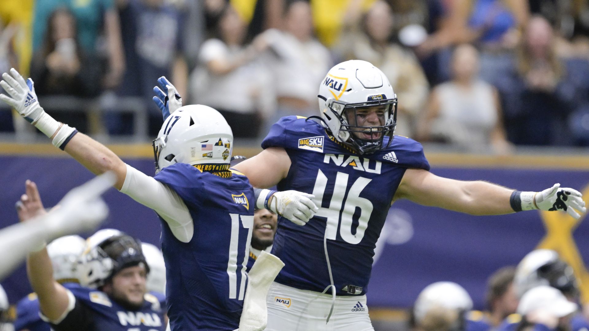 Two Northern Arizona University football players celebrate on the field. 