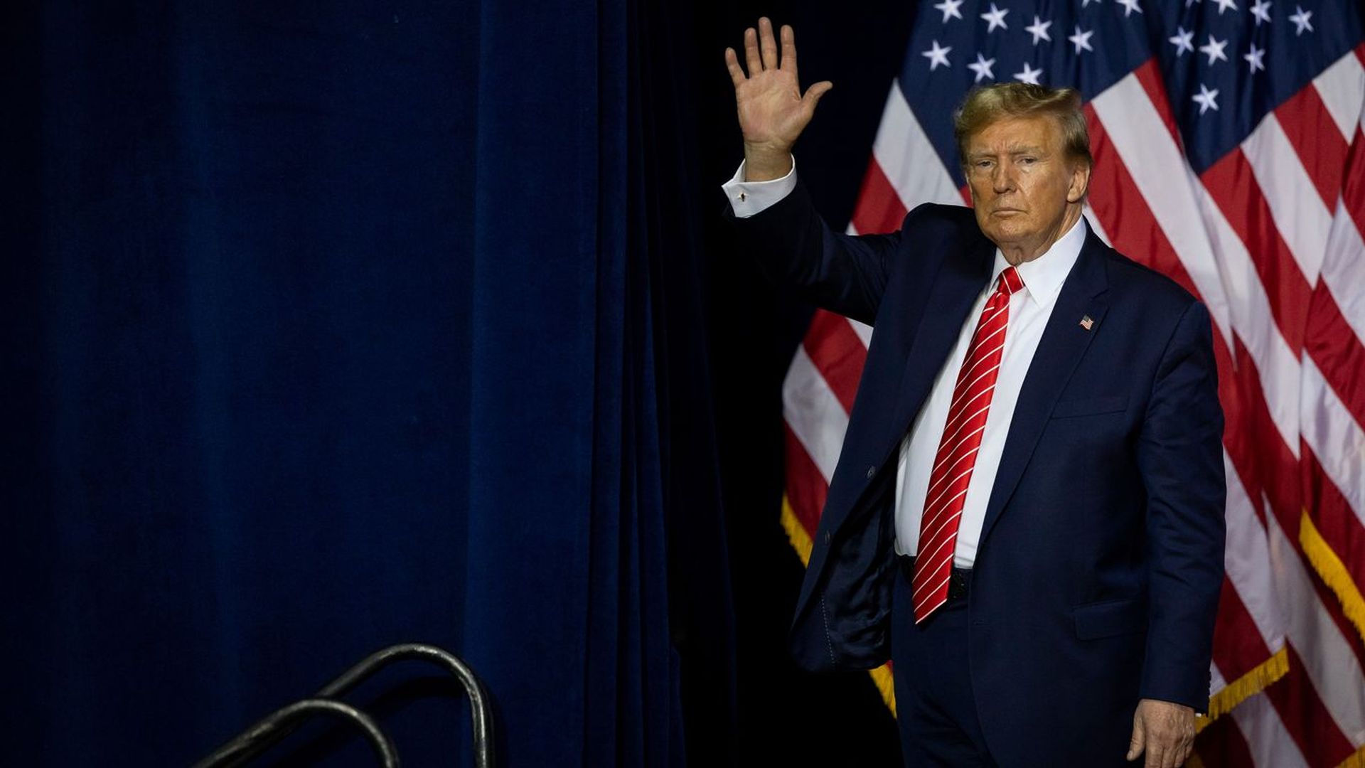 Photo of former President Trump waving in front of Americans flags.