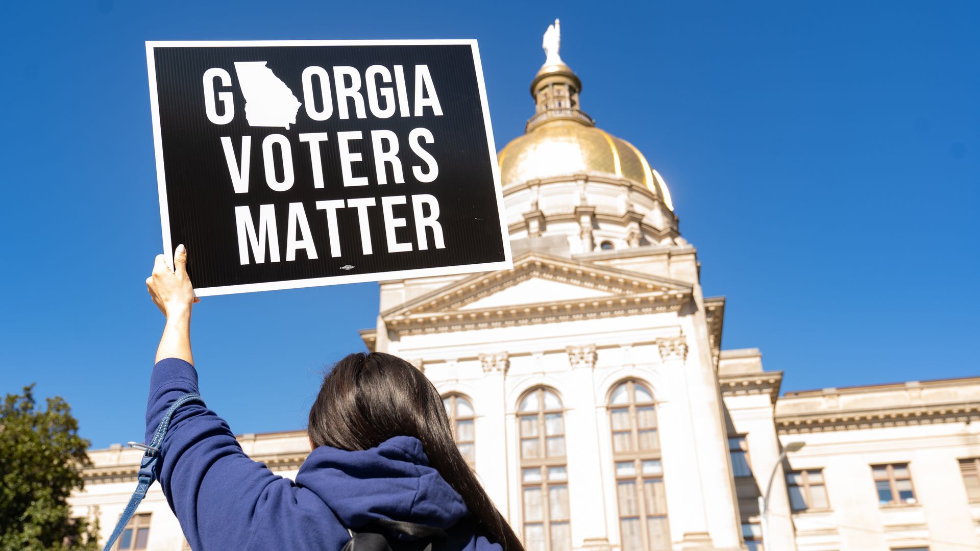 picture of the back of a person holding a sign that reads "georgia voters matter"