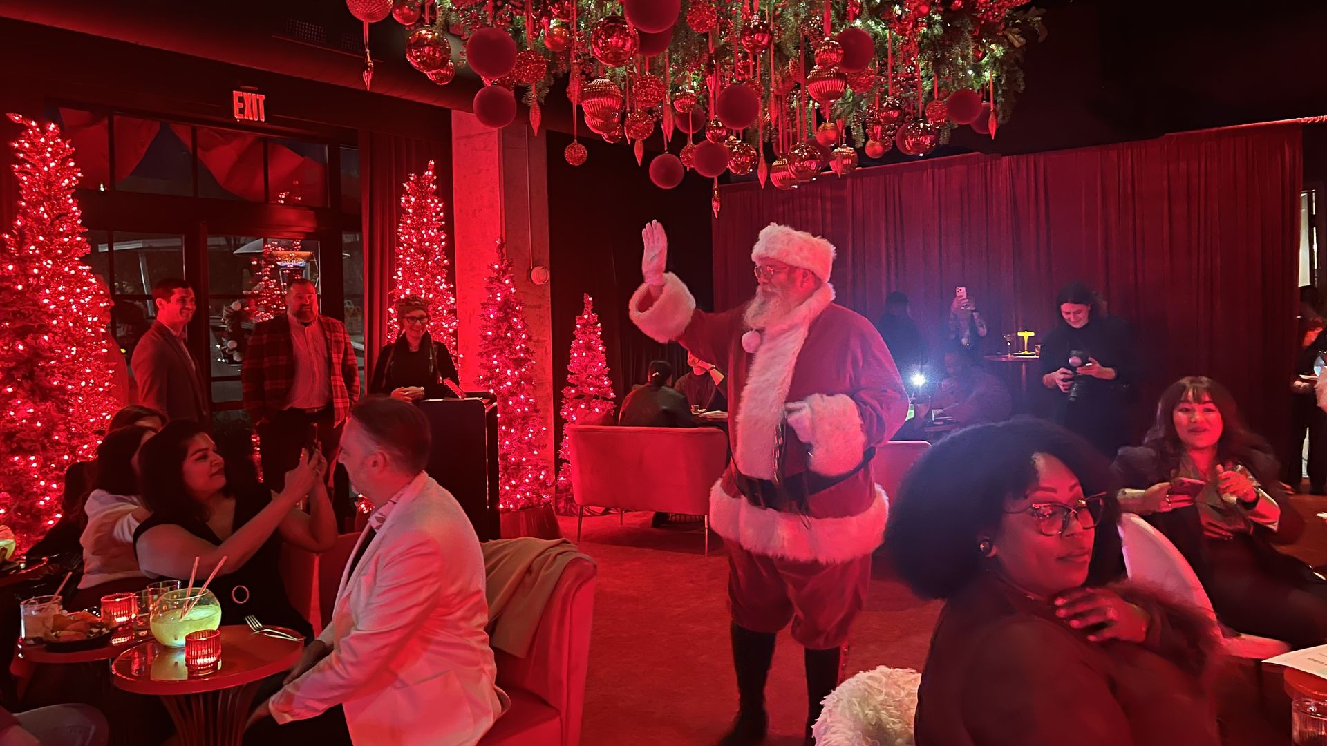 Santa waves at Santa Baby patrons inside the Junto