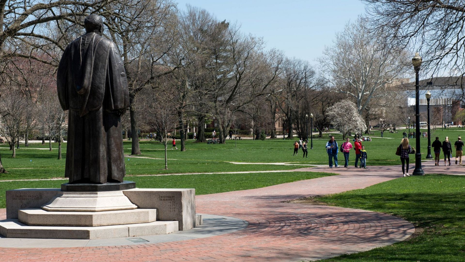 Students walk across the Ohio State University oval, near a statue of past OSU president William Oxley Thompson