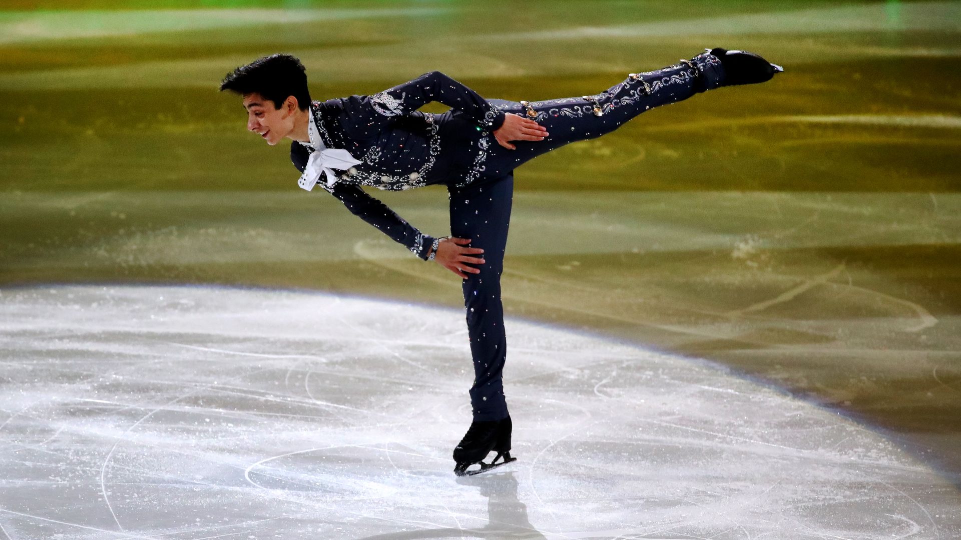 Mexican figure skater Donovan Carillo, dressed in a mariachi outfit, skates on ice, one leg in the air