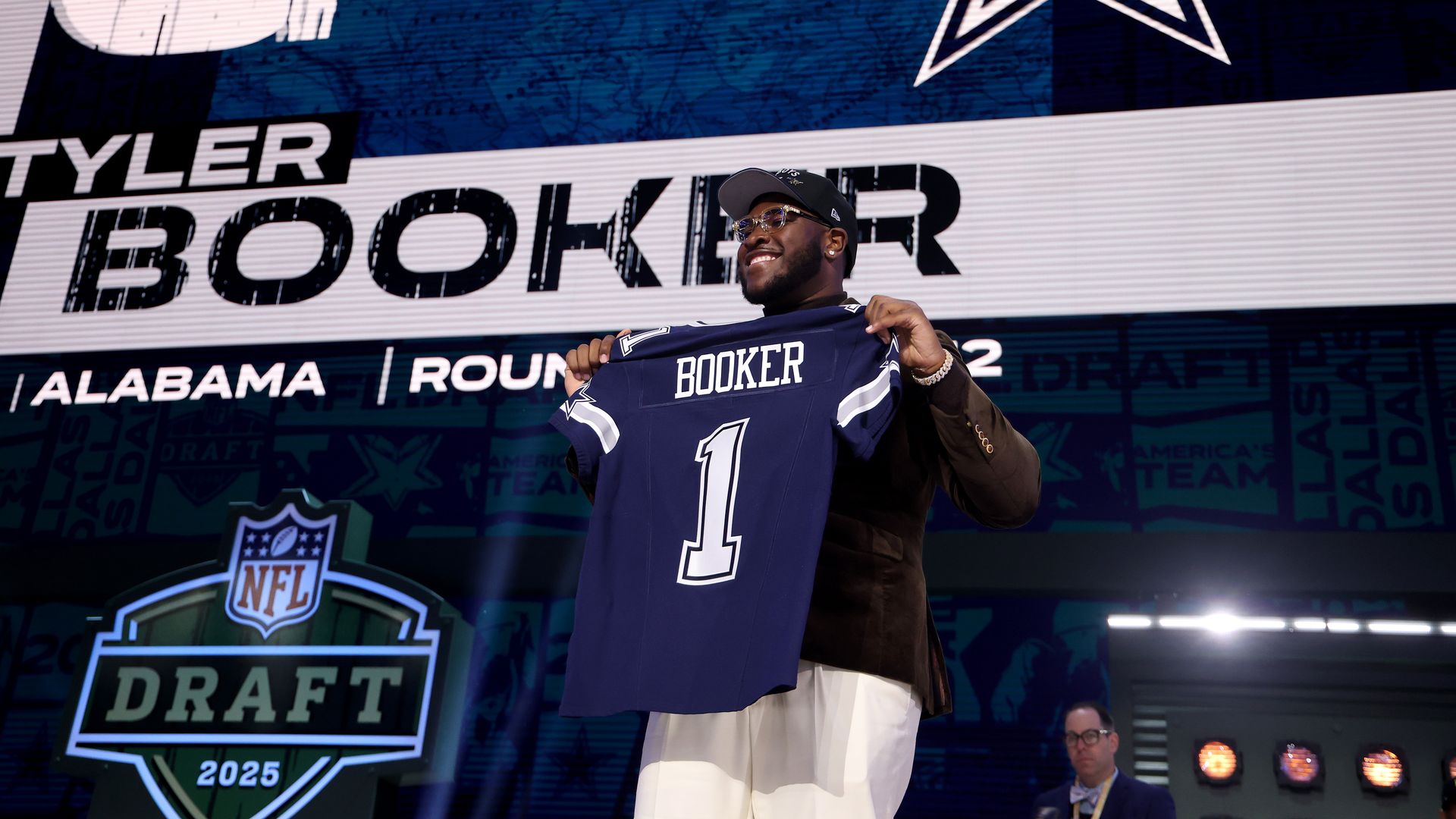 A man stands, holding a navy jersey that says "Booker" on it