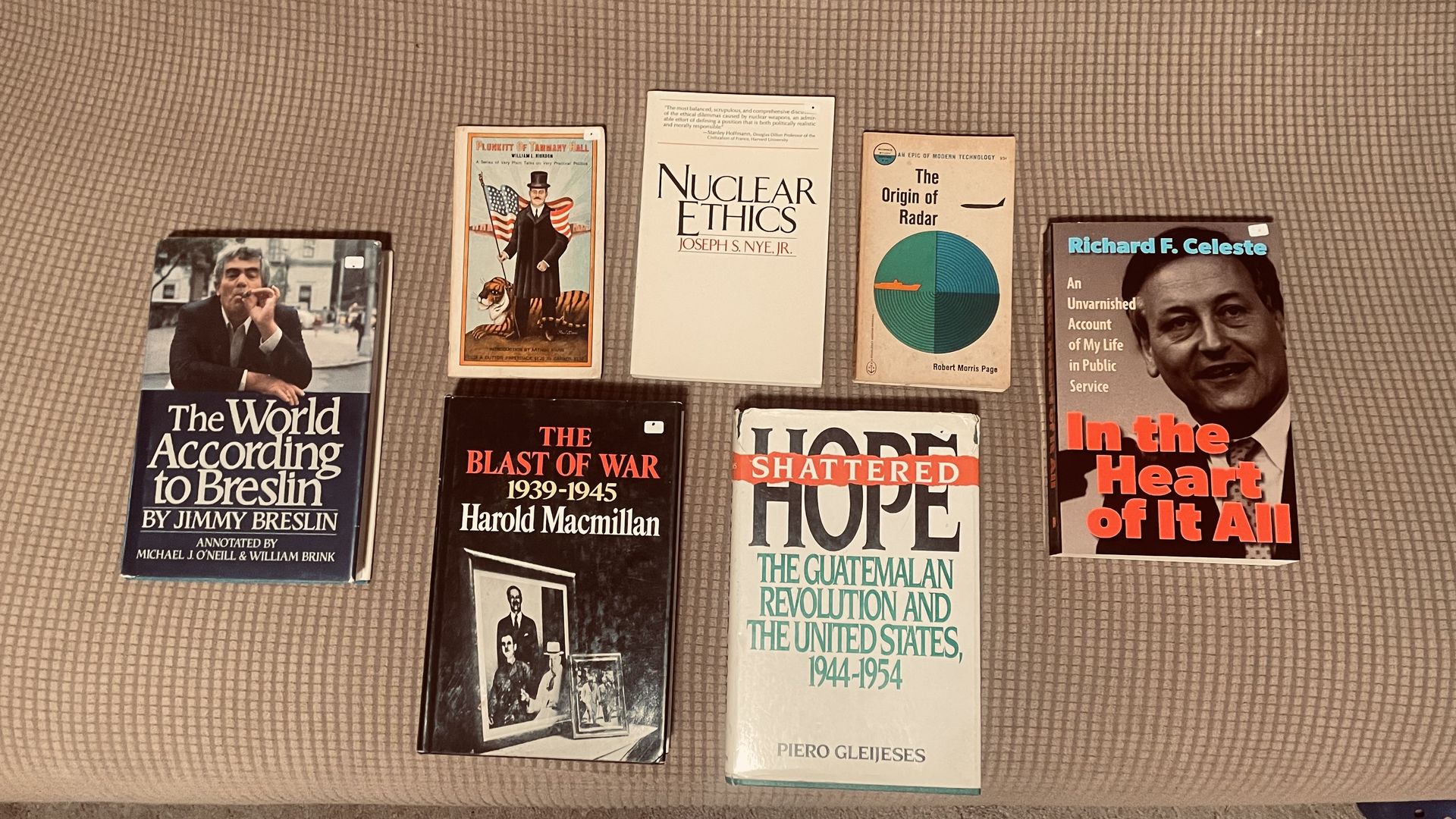 An array of seven used books on a couch.