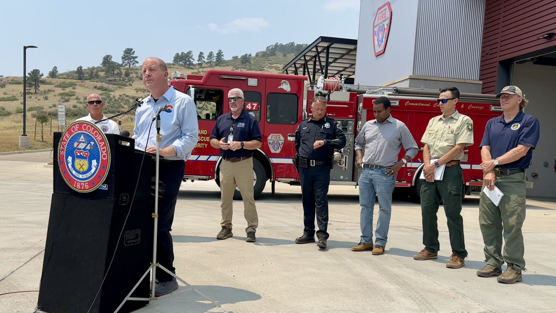 Gov. Jared polis, center, gives a briefing on Colorado wildfires with other officials standing by. Photo: John Frank/Axios