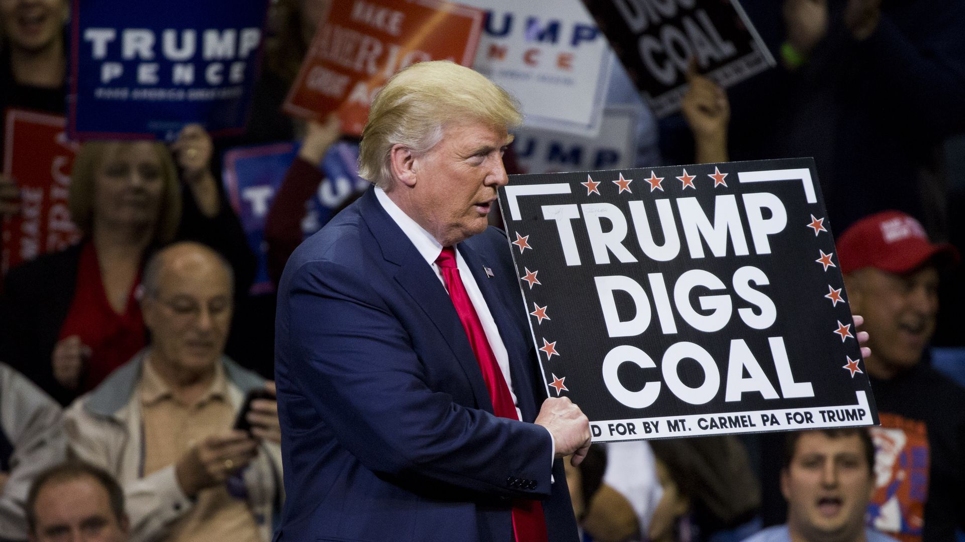 Trump holding a "Trump digs coal" sign