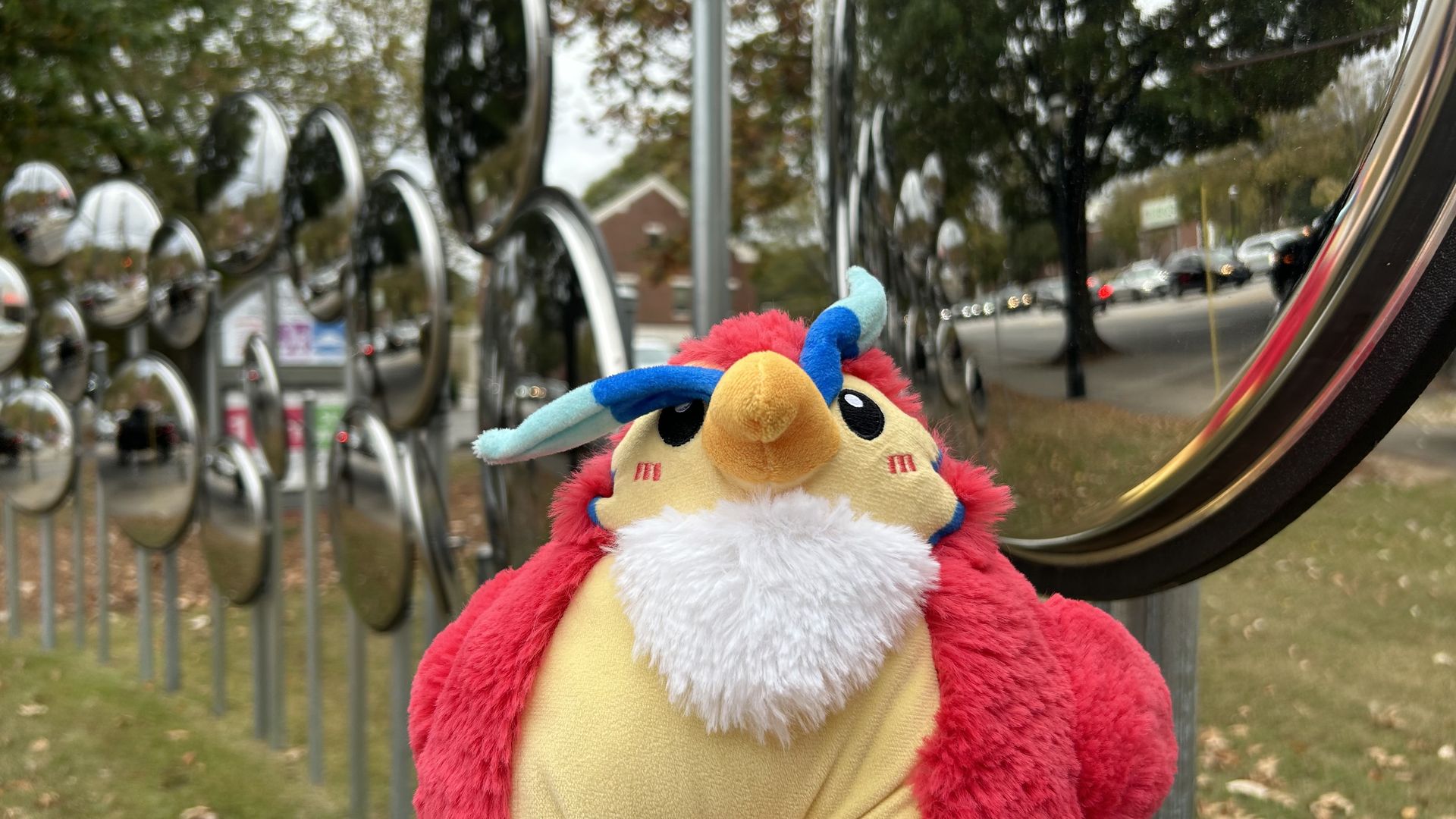 A stuffed animal Phoenix sits in front of round mirrors outside a building