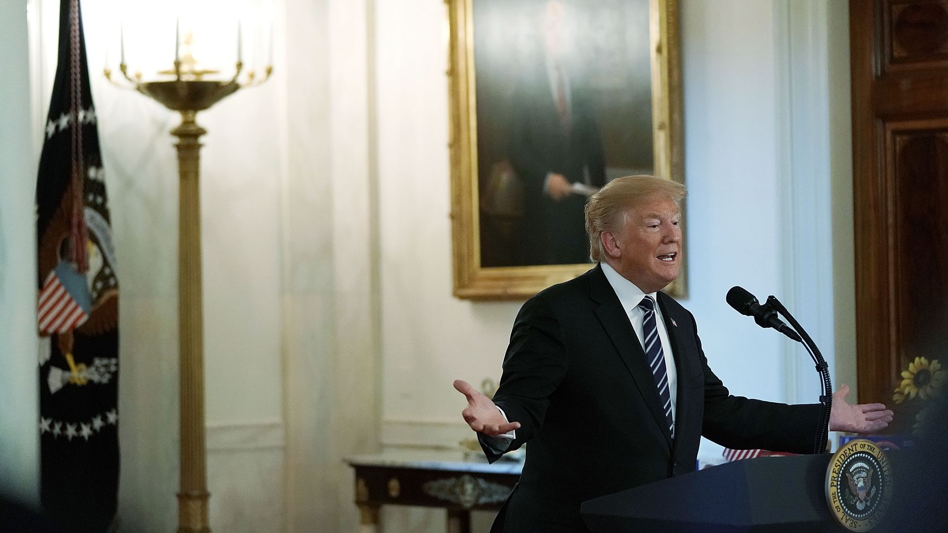 Donald Trump speaking at a podium. 