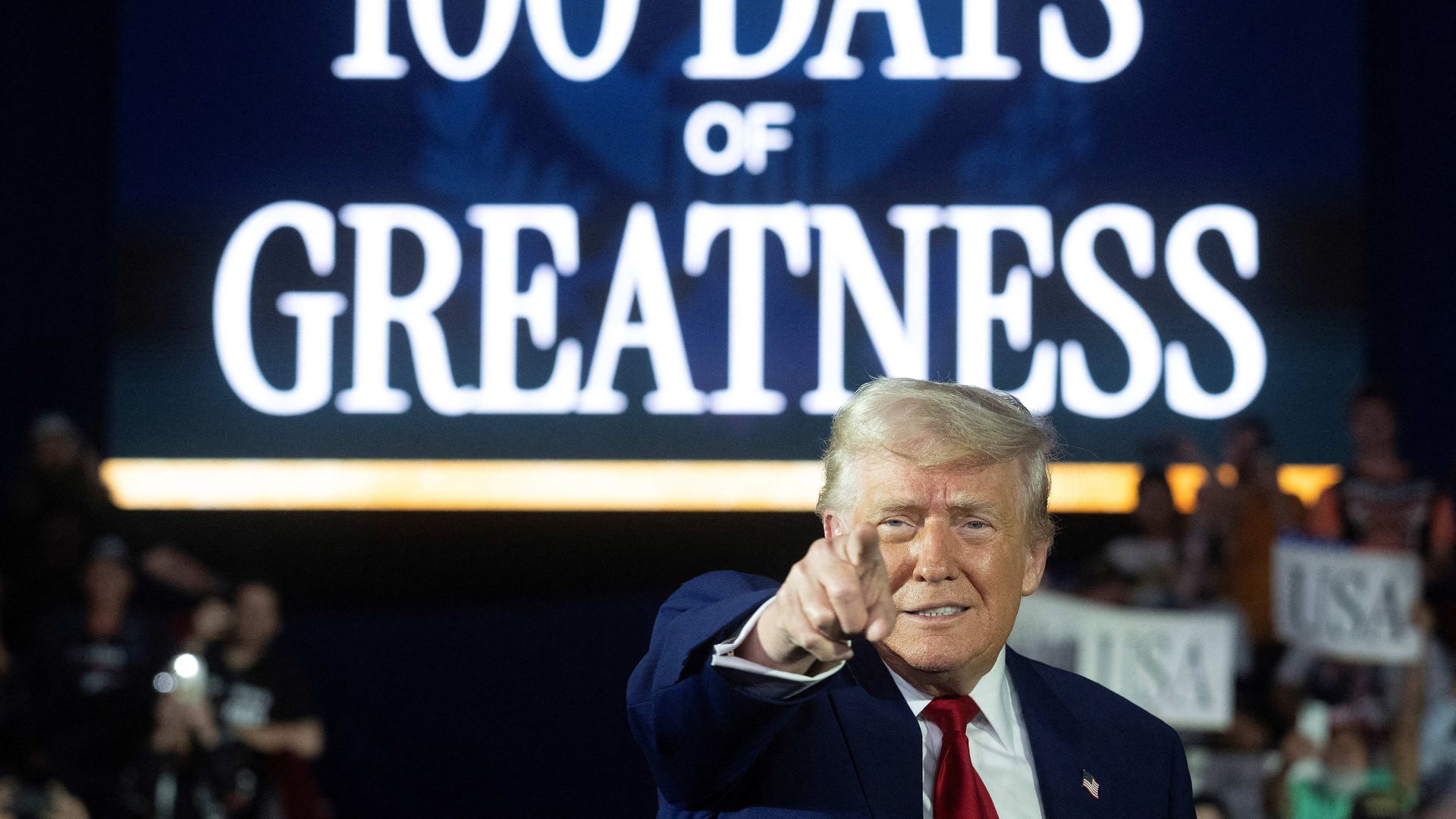 President Trump points behind 100 Days of Greatness in all capital letters