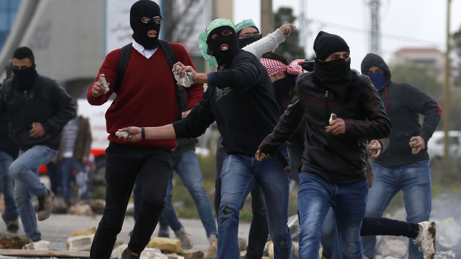 Masked Palestinian youths throw stones during clashes with Israeli soldiers
