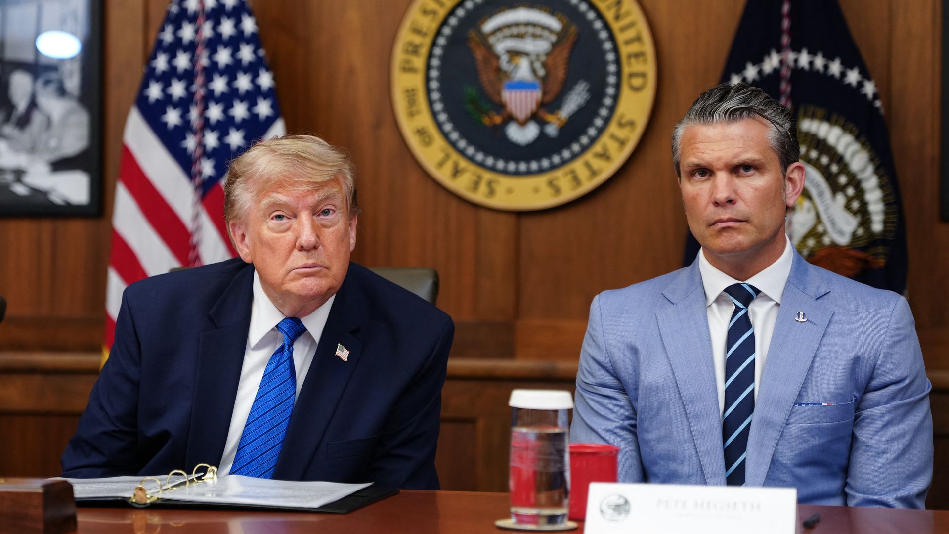 President Trump and Defense Secretary Pete Hegseth, seated side by side in front of the presidential seal.