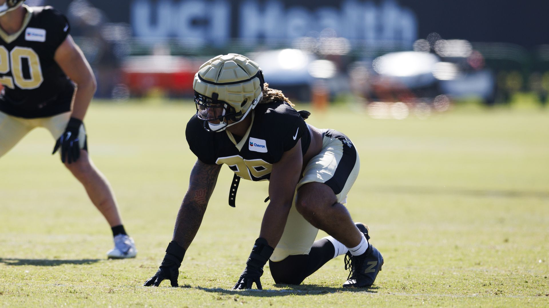 Chase Young kneels on the ground during a practice as though he's about to rush forward.